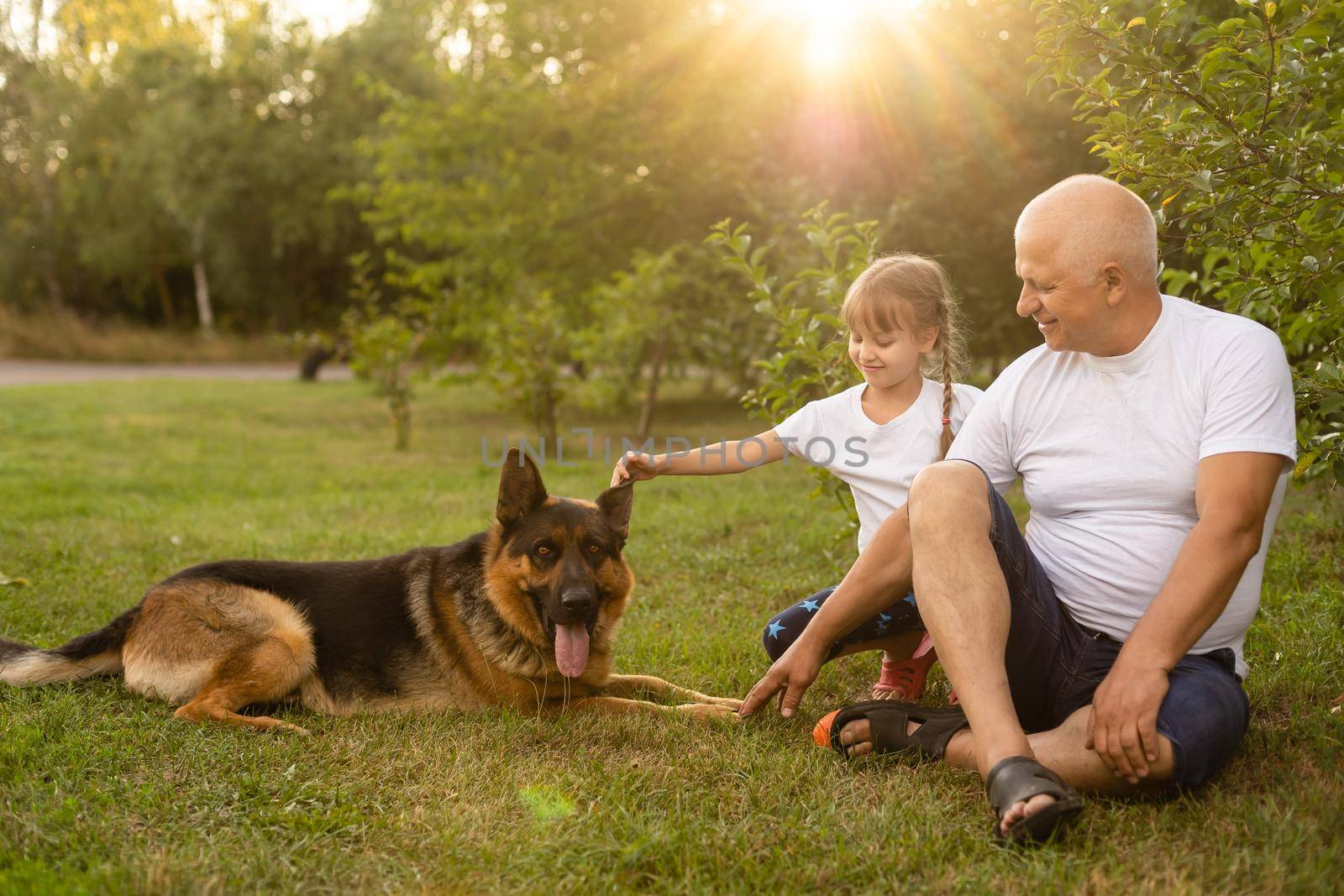 Grandfather with granddaughter and a dog in the garden