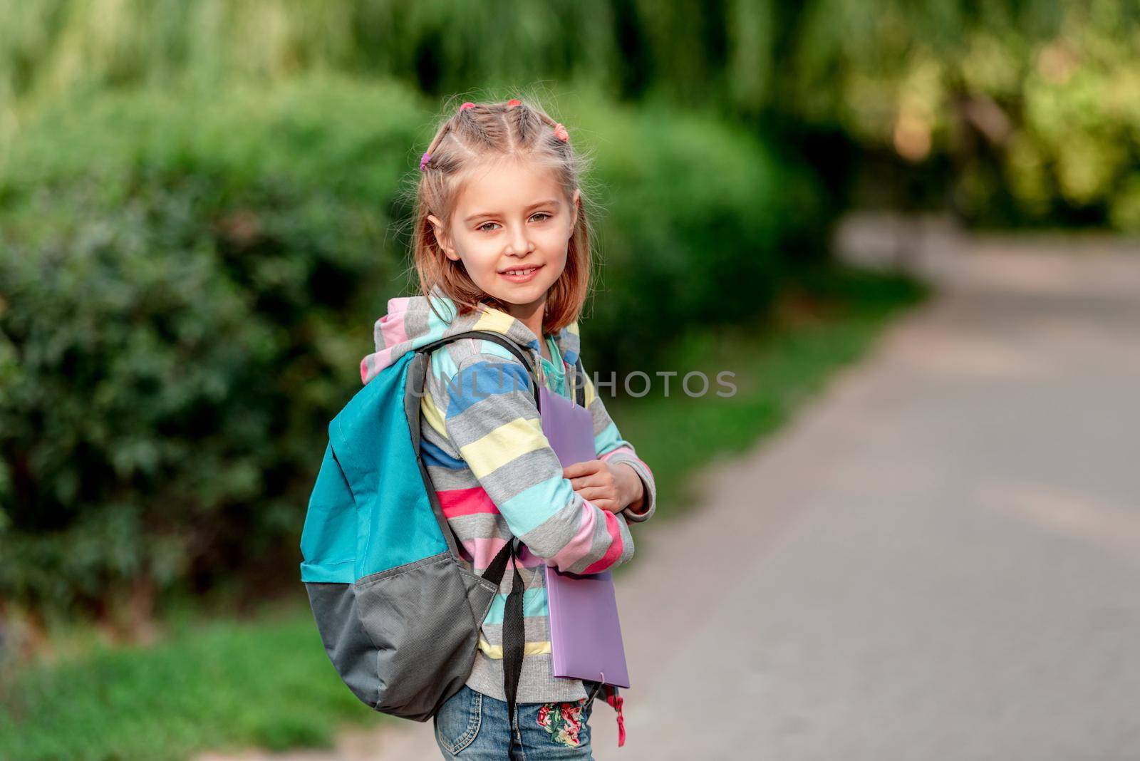 Portrait of little girl in mask running outdoors after schooling