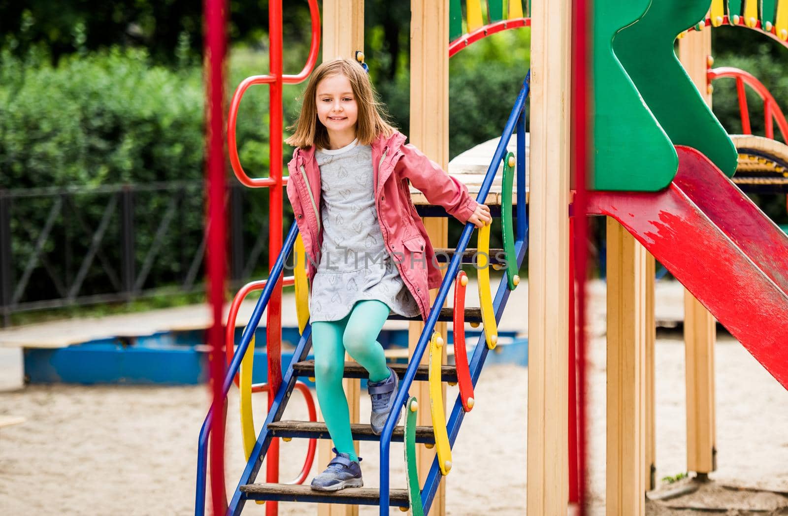 Little girl coming down ladder on playground in park