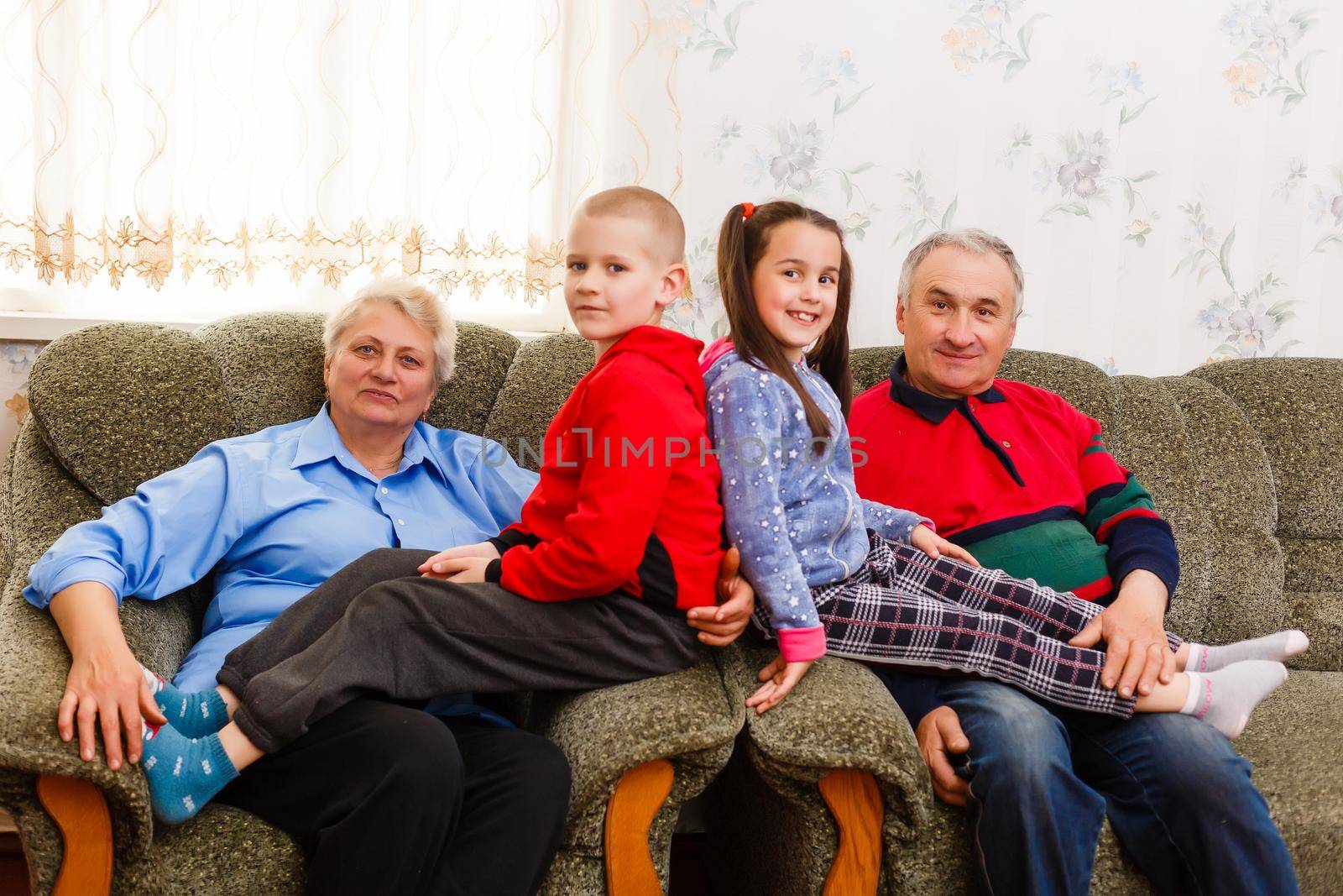 Grandparents and their young grandchildren relaxing at home