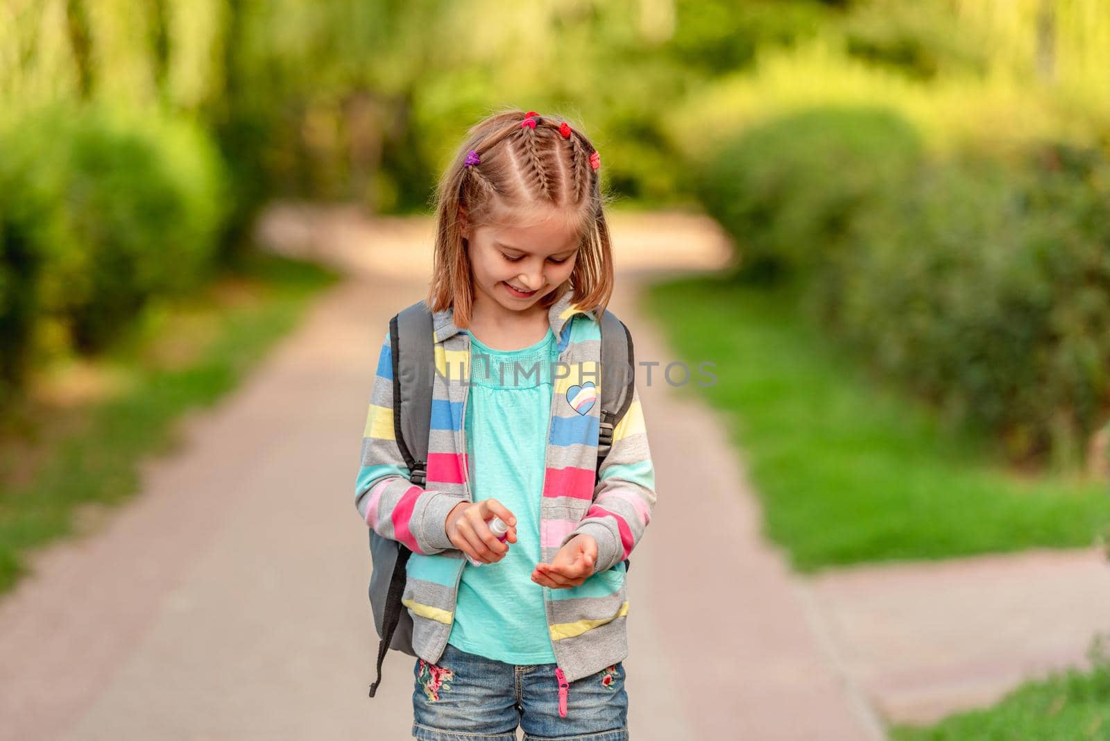 Little girl using hand sanitizer after school in park