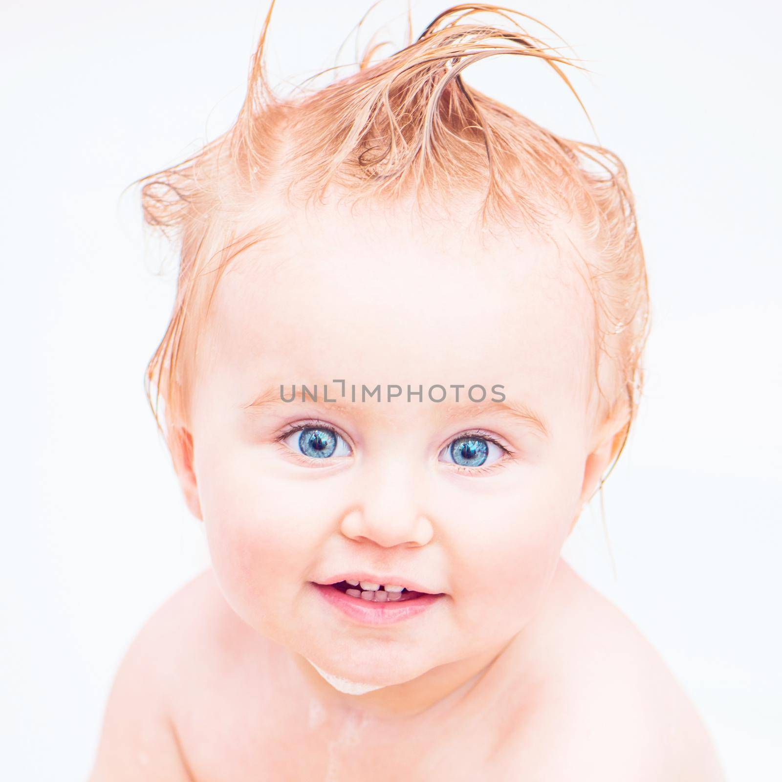 cute 1 year-old girl bathes in a bath with foam closeup