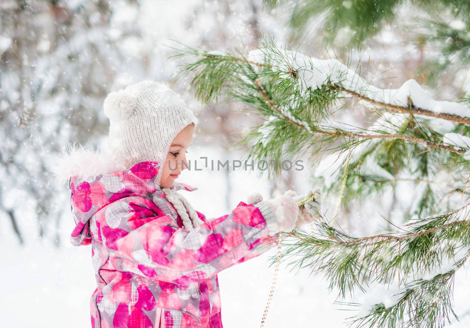 Little smiling girl decorating christmas tree outdoor
