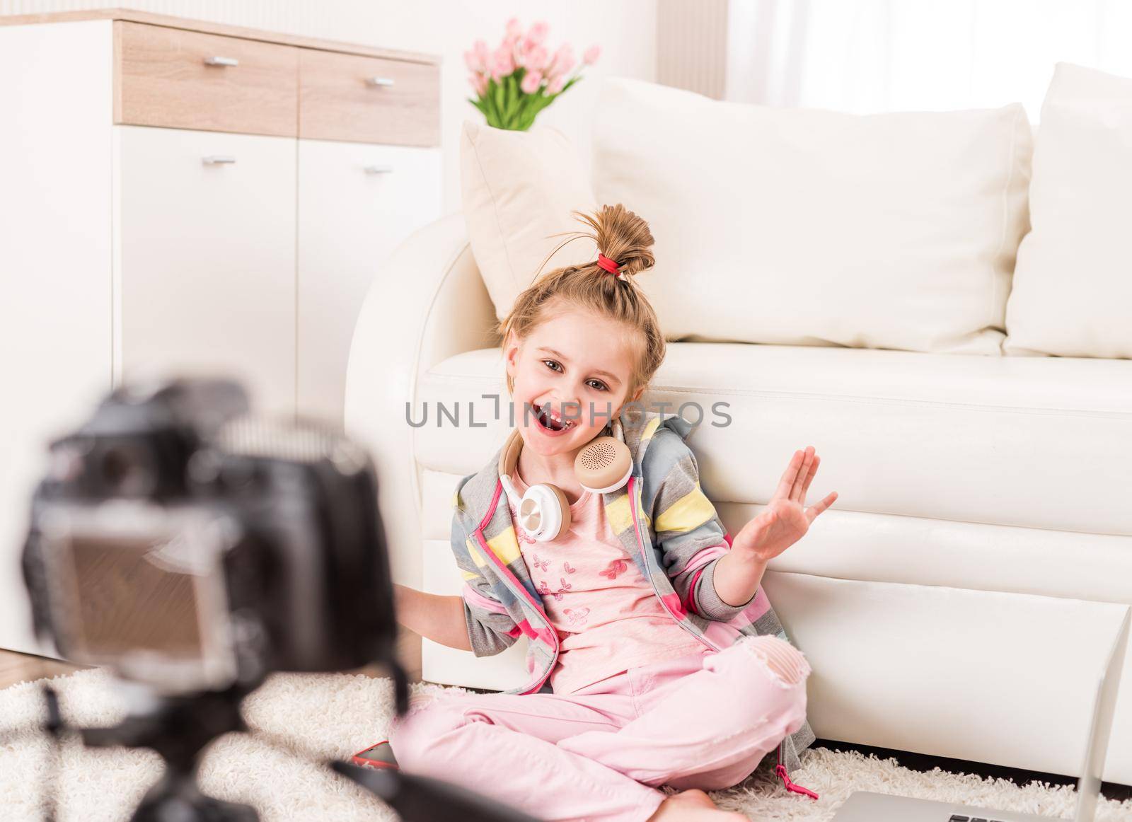 Happy smiling little girl recording video with headphones on