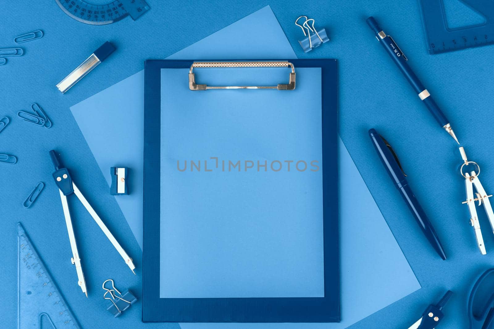 Classic blue colored top view photo of scattered stationery. Close up.
