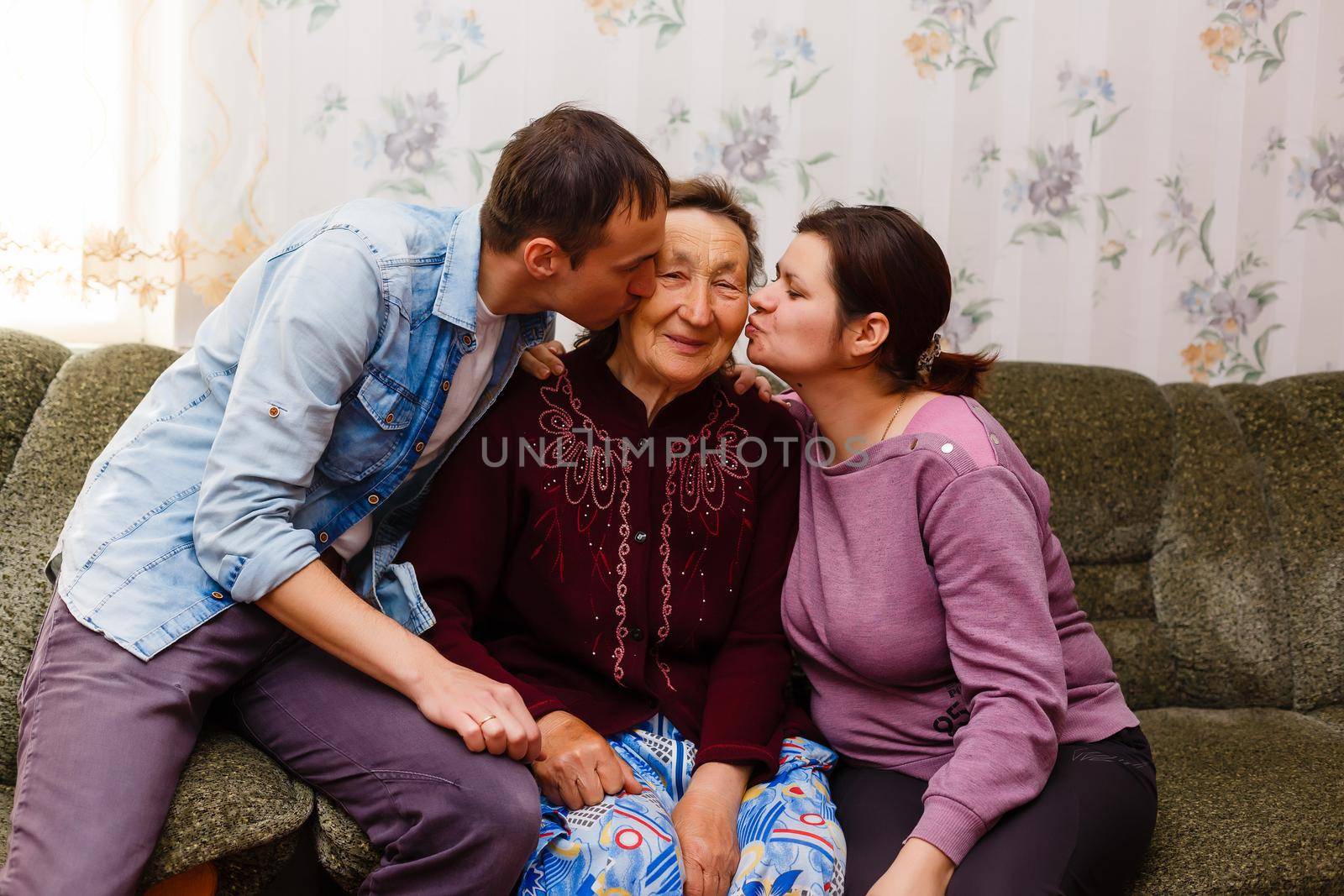 Grown up adult smiling grandchildren embraces elderly grandmother glad to see missing her, visit of loving relatives enjoy communication, cuddle as symbol of connection, love and support concept