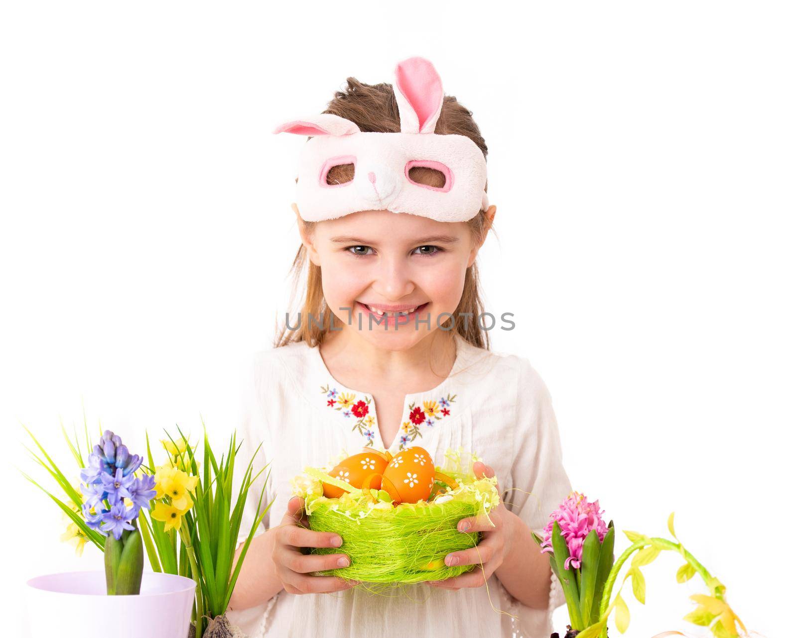 Smiling girl with vine basket of celebrative items, prepared for Easter, on white background