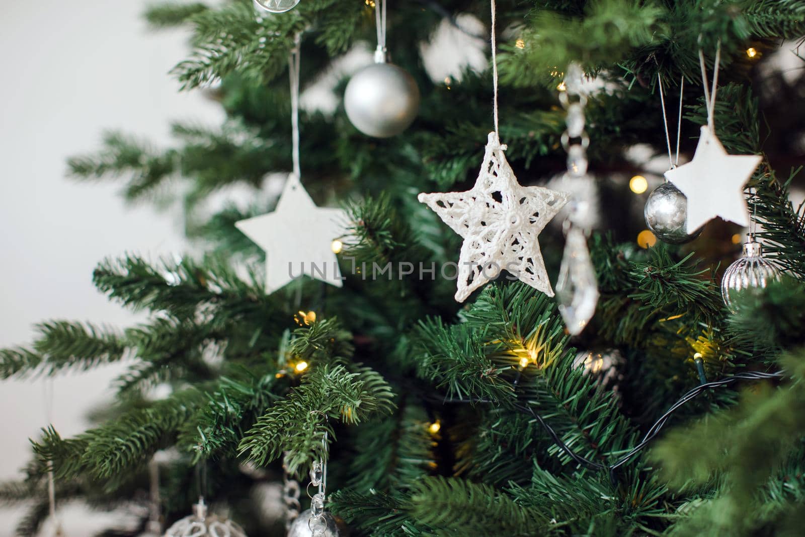 Close-up of white handmade stars decorating Christmas pine tree.