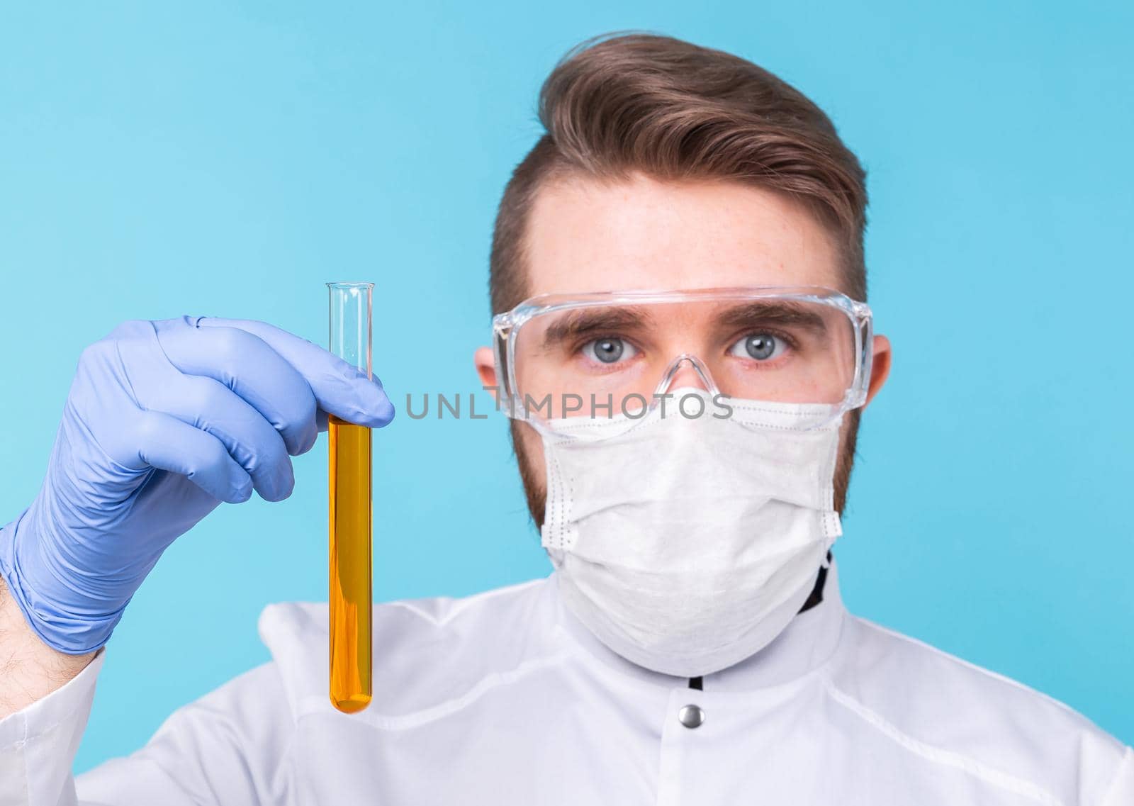 Covid-19, Vaccine development, pandemic, outbreak and medicine concept - Man scientist in mask and protective gloves holding a test tube.