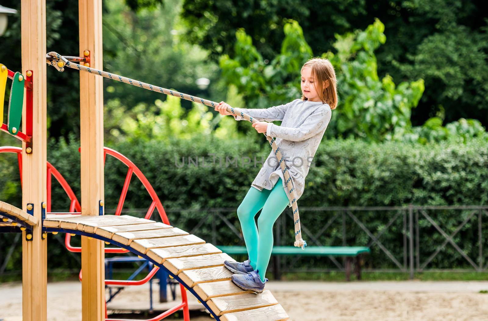 Child climbing with rope on sport playground outdoors at sunny day