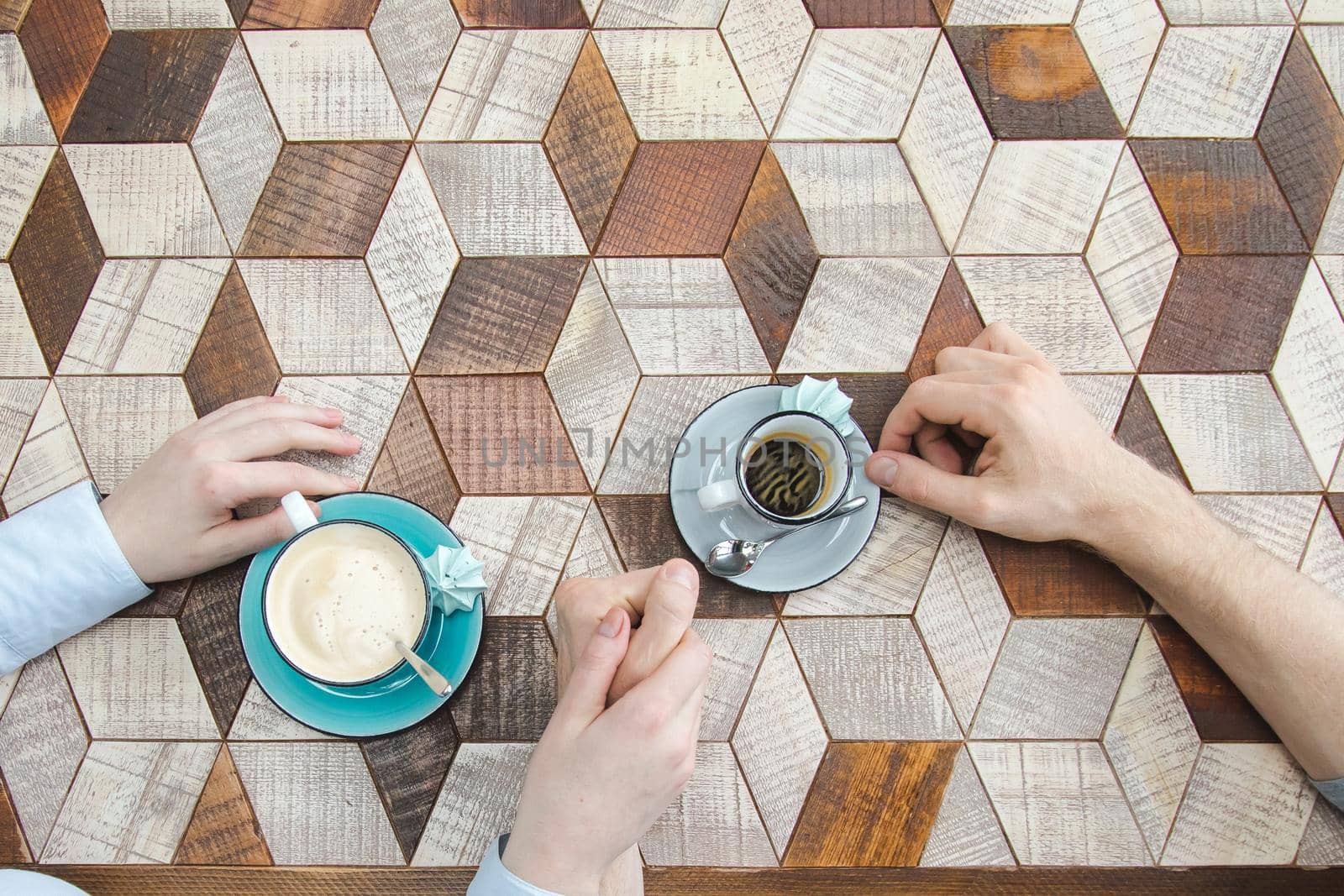 Top view of couple holding by hands and drinking coffee beautiful wooden countertop mosaic