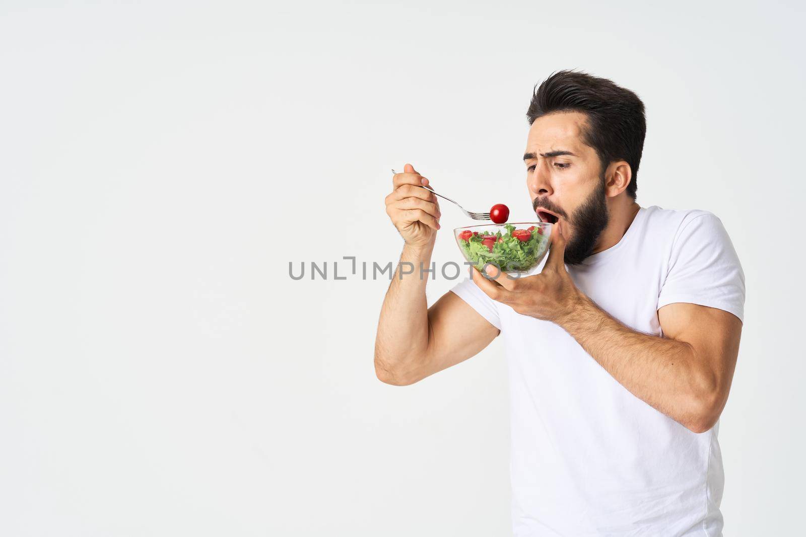 a man in a white t-shirt in a plate with salad a snack healthy food. High quality photo