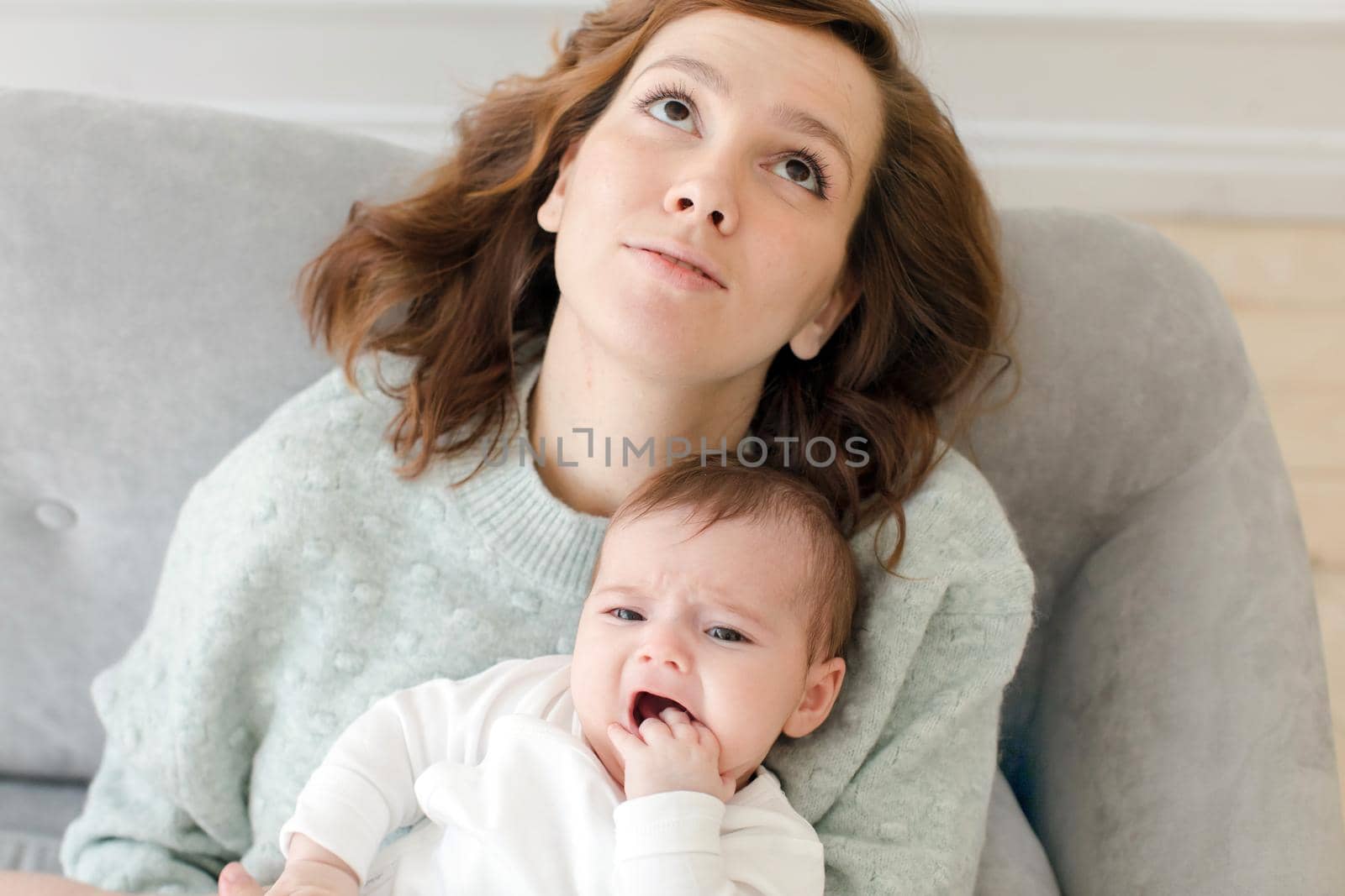 Young mother holding baby on knees and looking up by Demkat