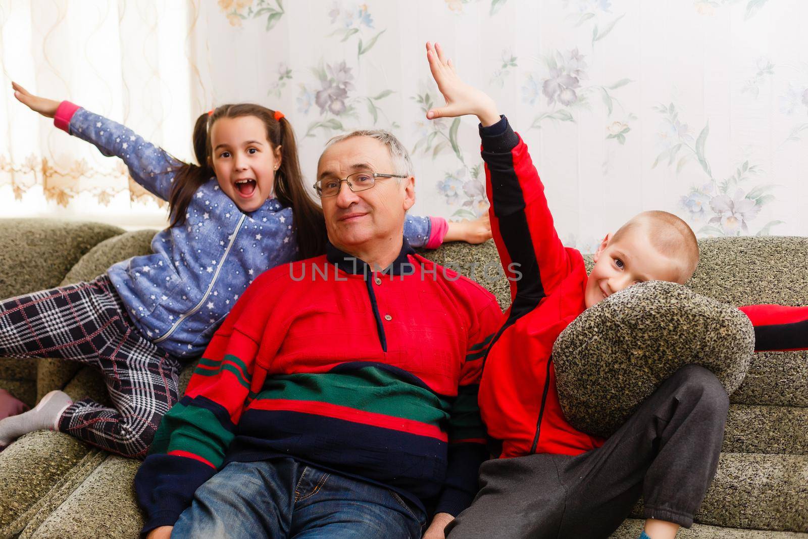 Grandparents spending time with grandchildren on couch by Andelov13