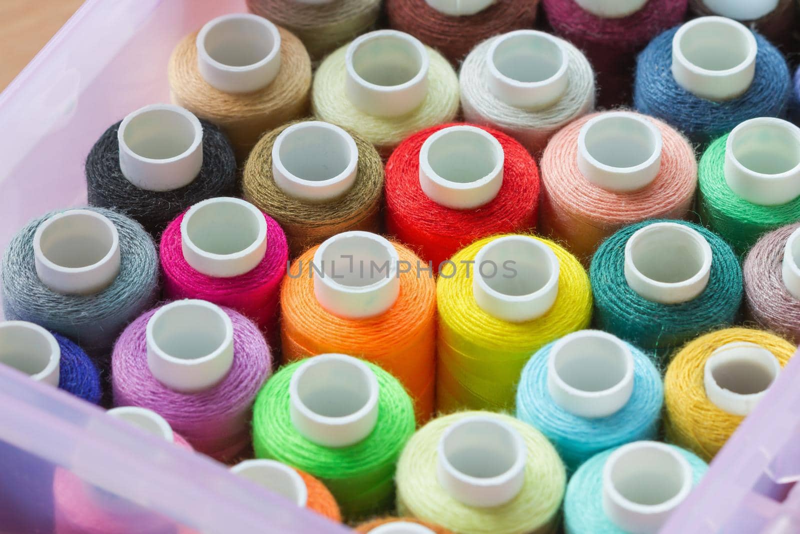 A lot of colorful sewing threads in the box. Selective focus, closeup.