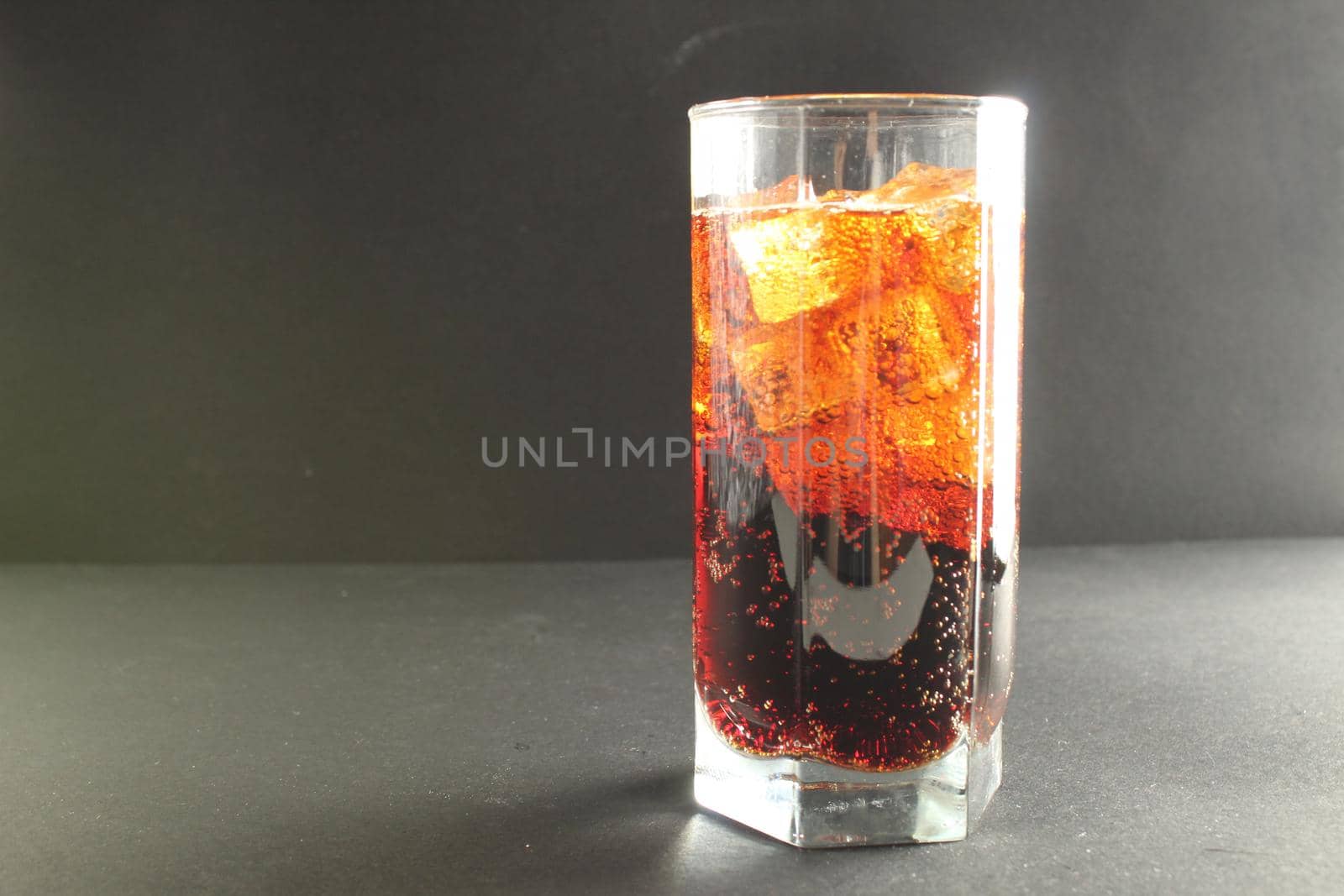 Coca-Cola kvass in an iced glass on a gray background with room to text a cold refreshing summer drink.