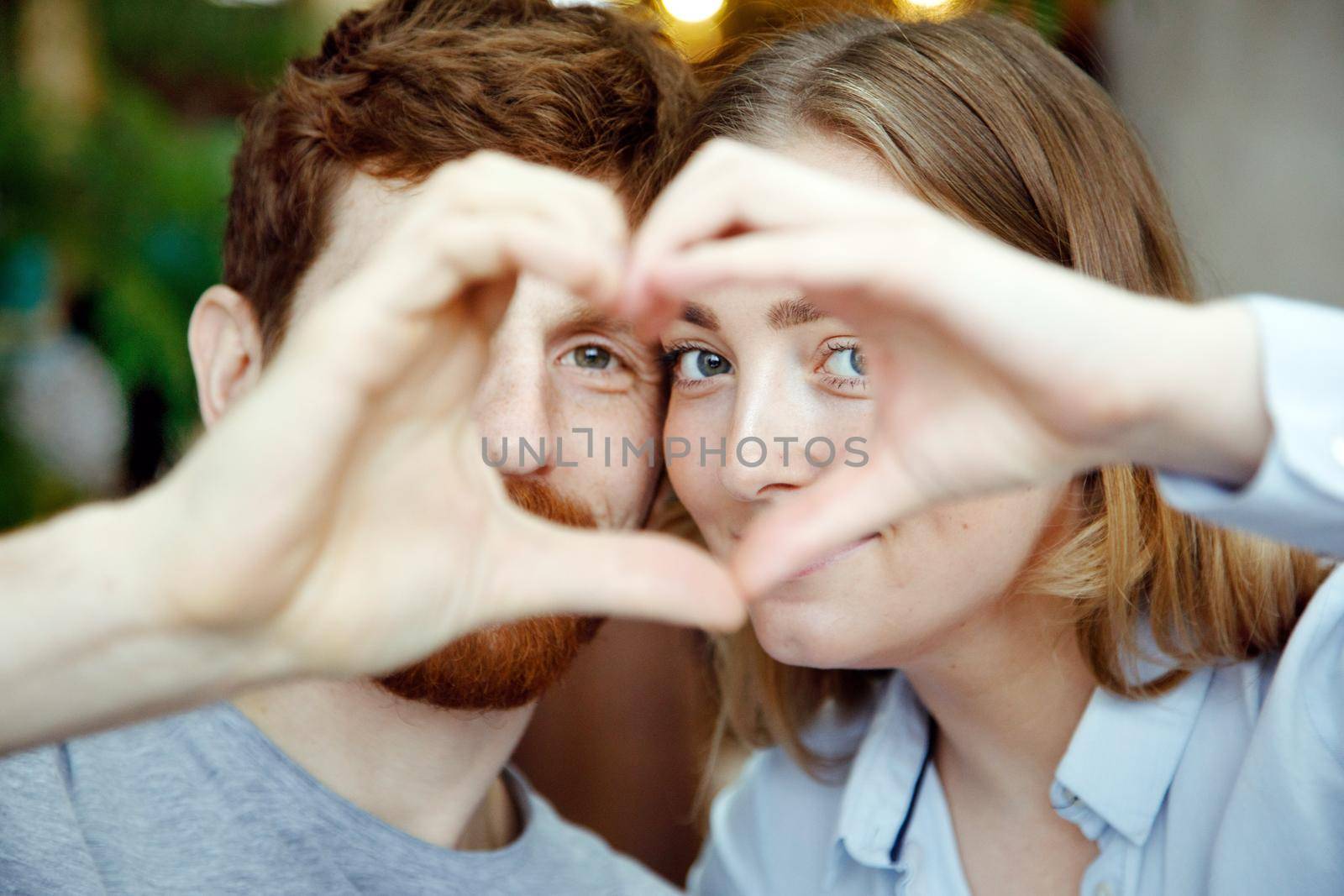 Young loving couple stacking hands creating heart while posing contently together.