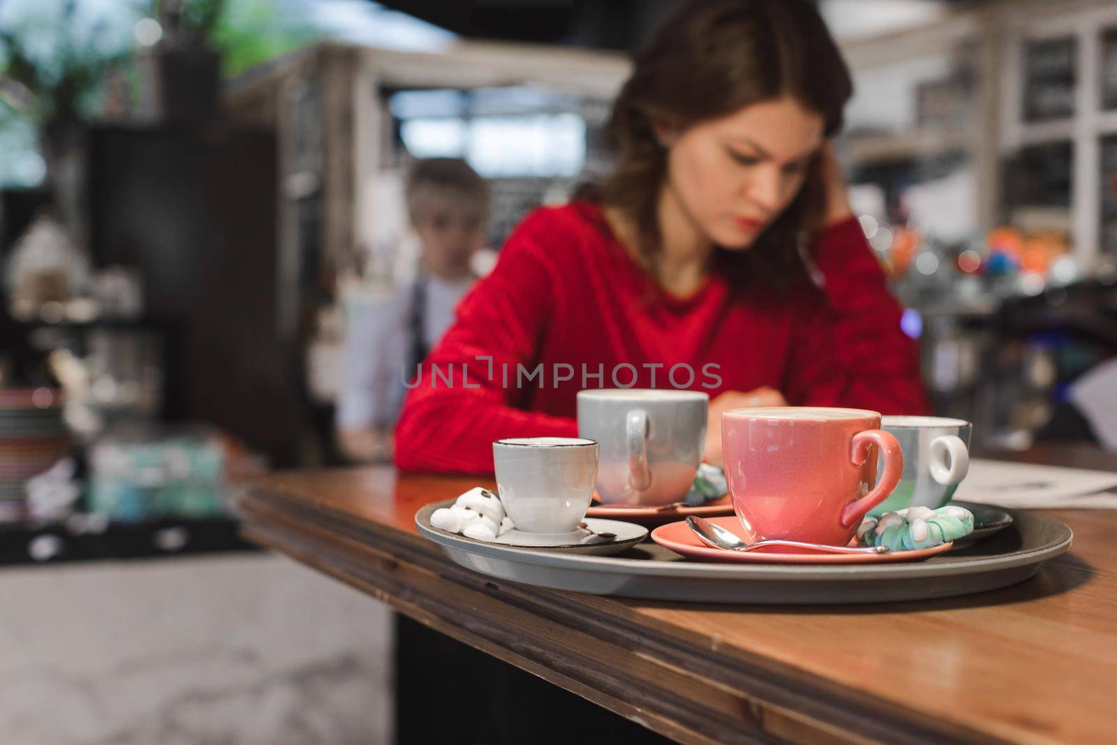 Assortment of cups with coffee drinks on the background of a busy girl