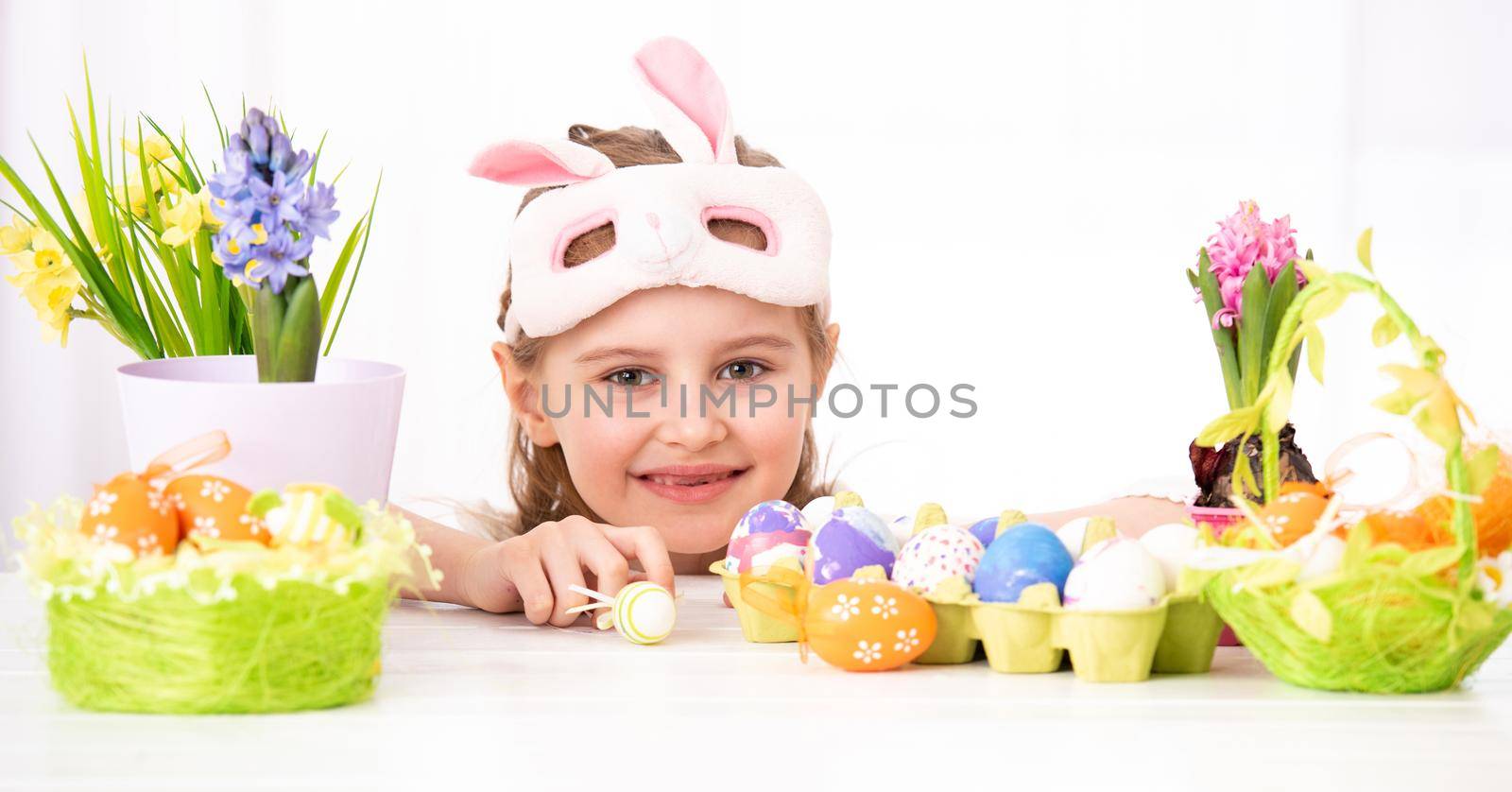 Happy smiling child peals from behind traditional and beatiful Easter decorations, isolated on white background