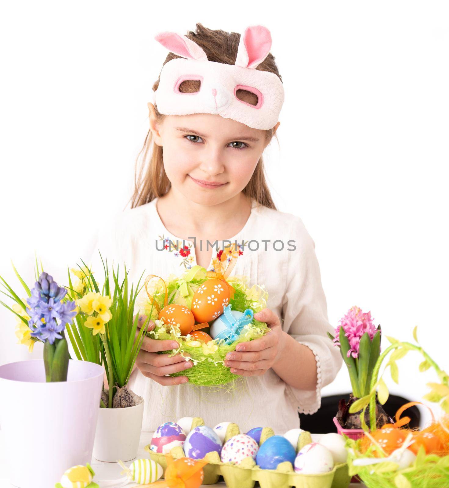 Smiling girl with vine basket of celebrative items, prepared for Easter, on white background