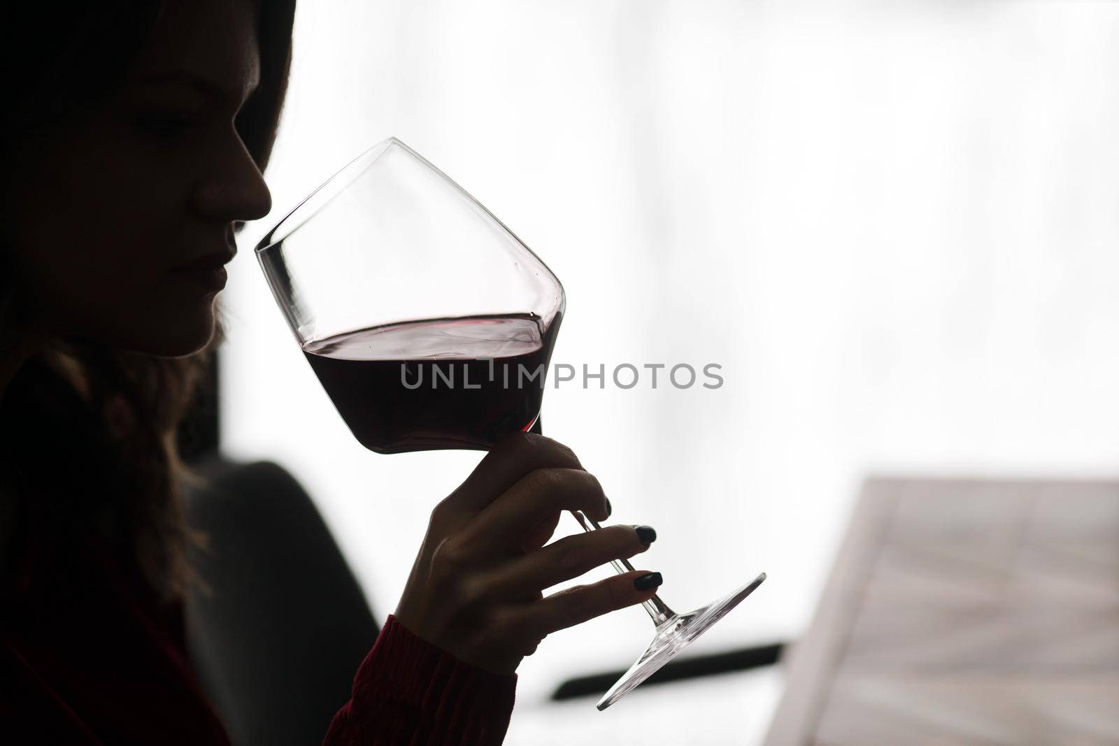 A young girl takes a sip of red wine in a restaurant