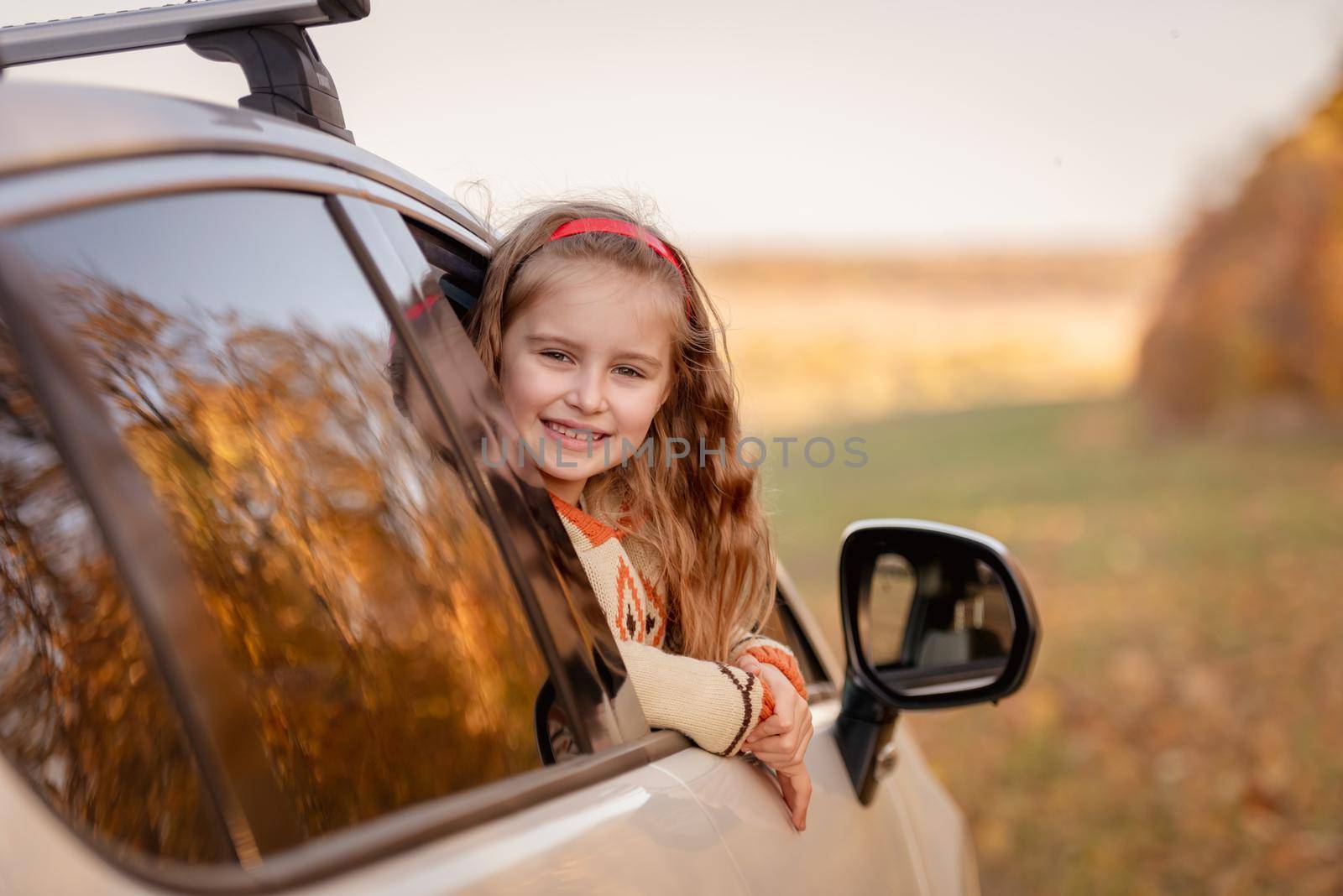 Cute little girl in car on autumn background