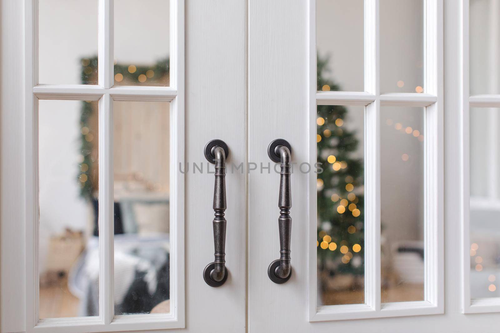 Wooden opened doors showing view of bedroom interior with Christmas tree glowing.