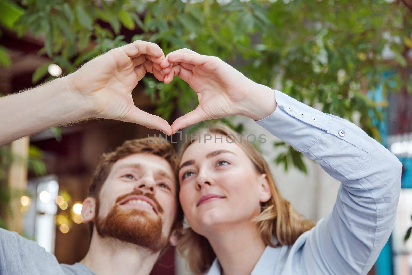 Young loving couple stacking hands creating heart while posing contently together.