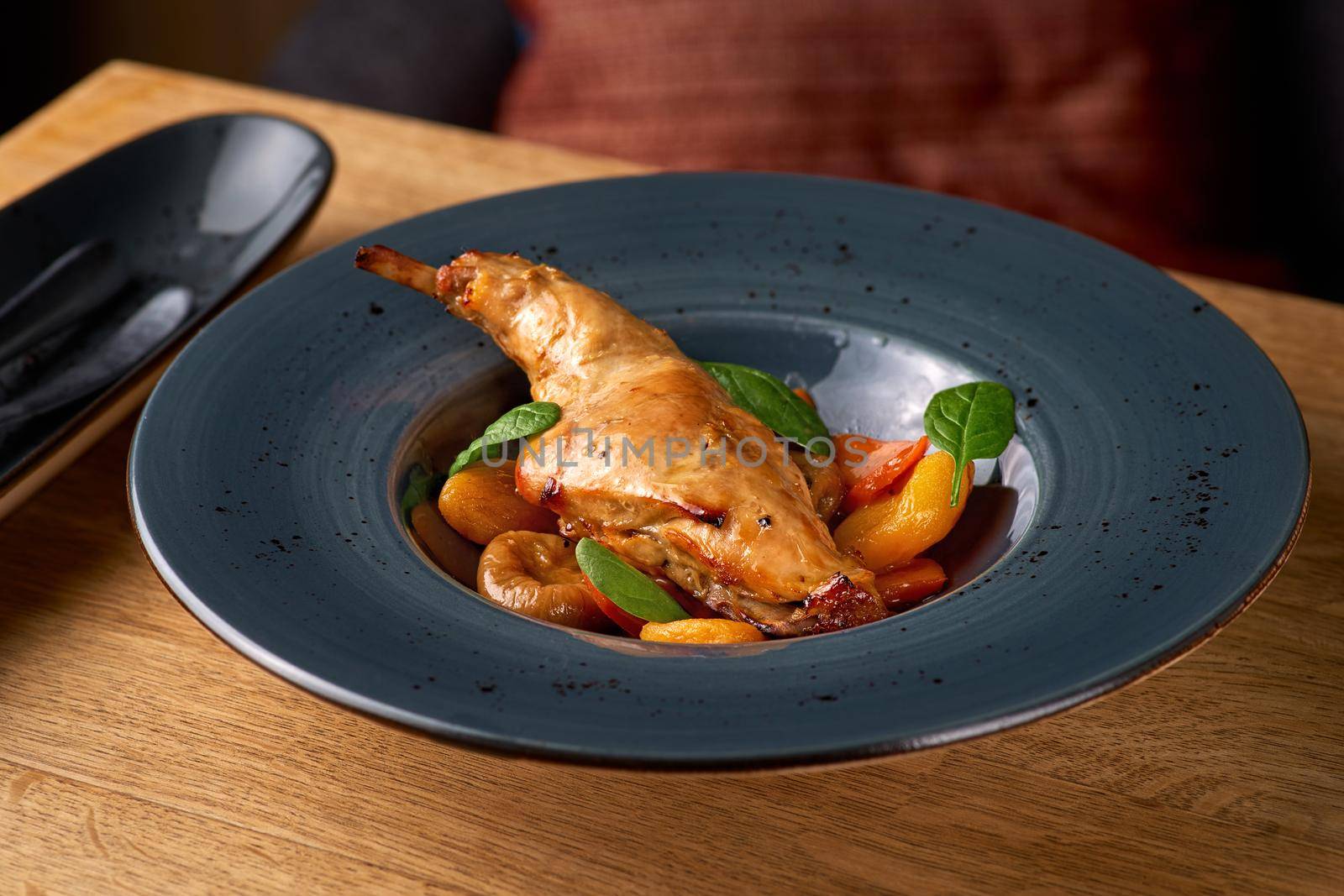 Tasty spicy rabbit stew in tomato sauce with white wine and herbs close-up on the table, serving in a restaurant, menu food concept.