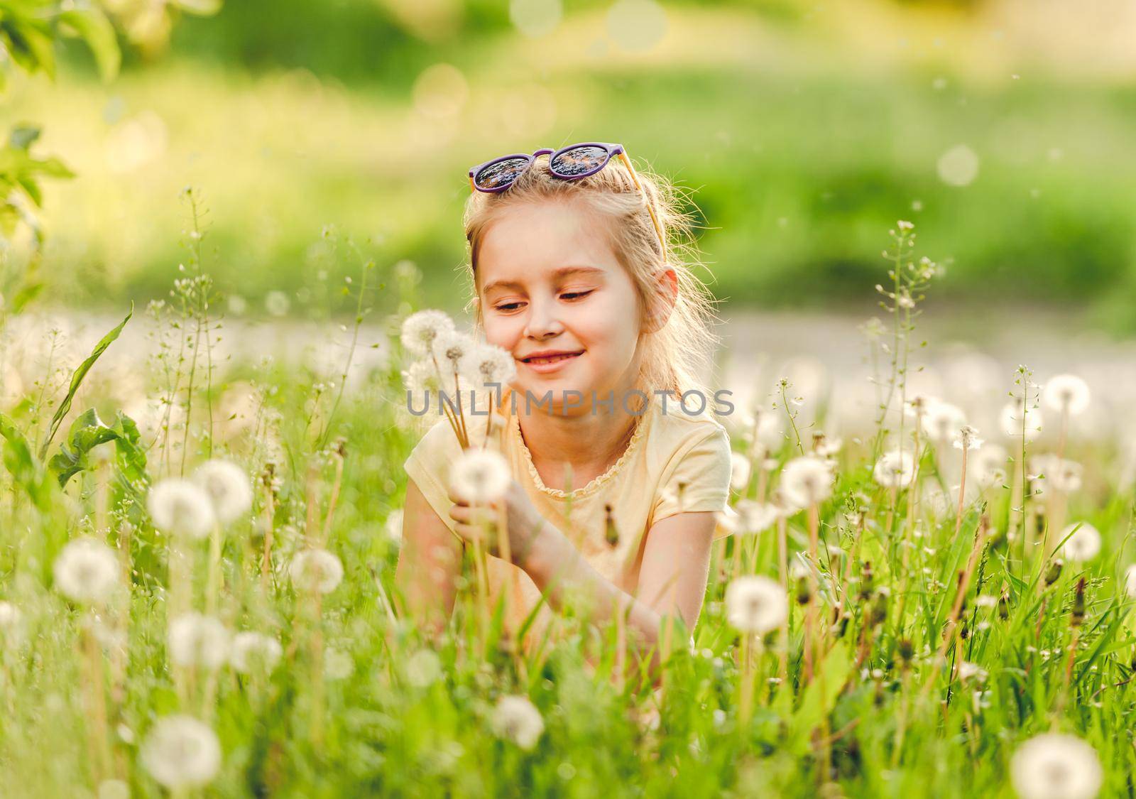 Child playing on the nature, on meadow, with flowers dandelions
