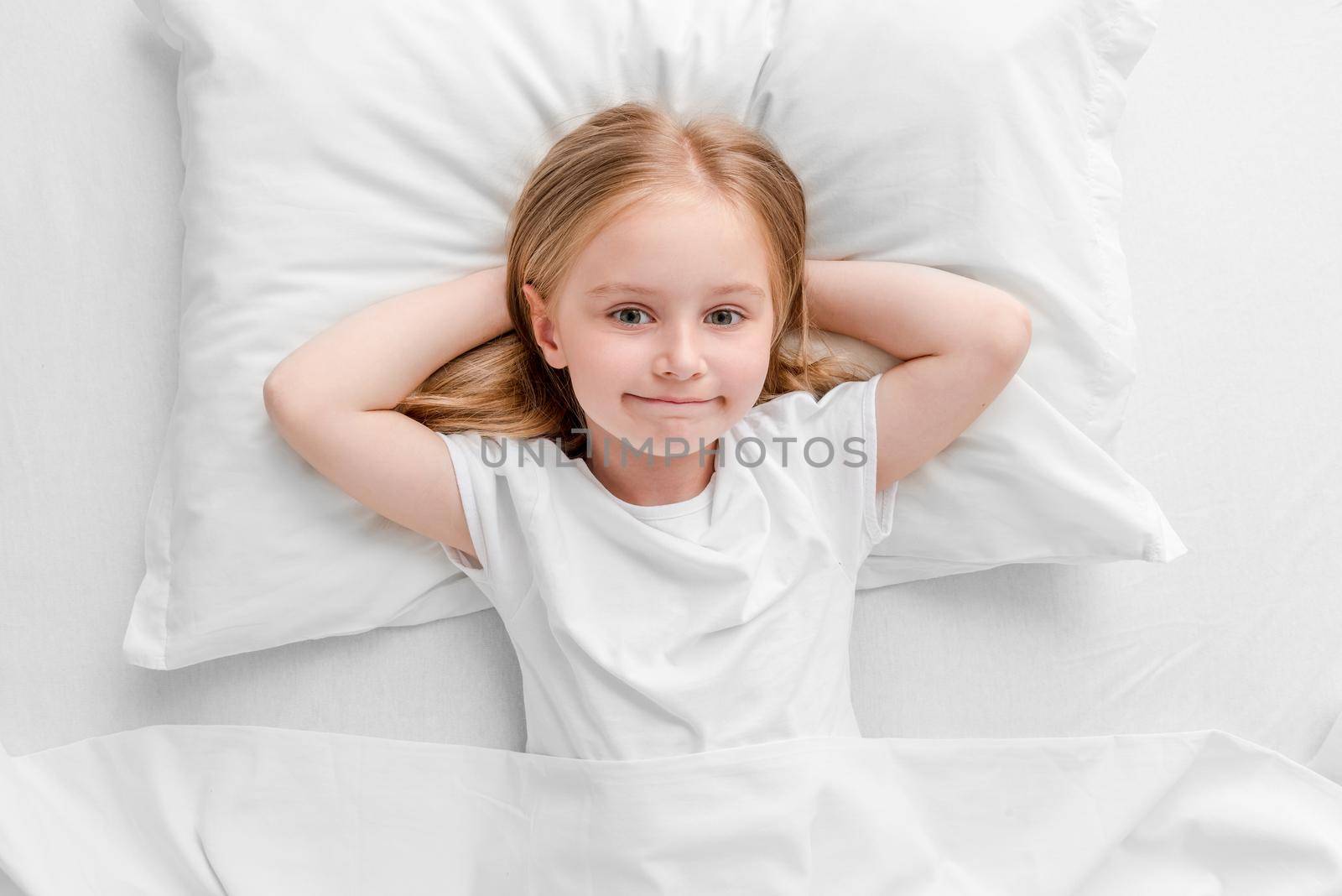 cute smiling little girl woke up in white bed