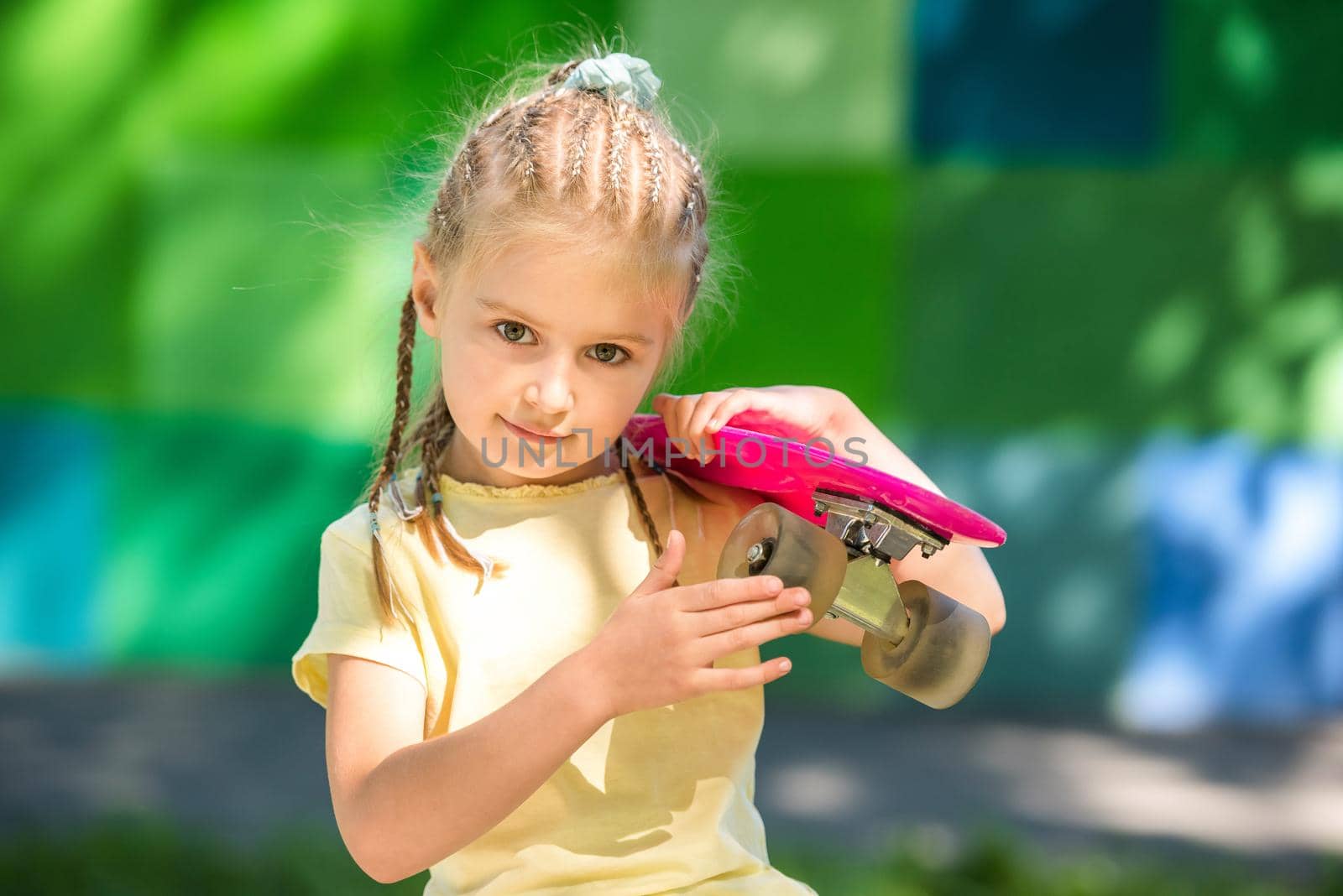 cute little girl with a skateboard on her shoulder in the afternoon in the park