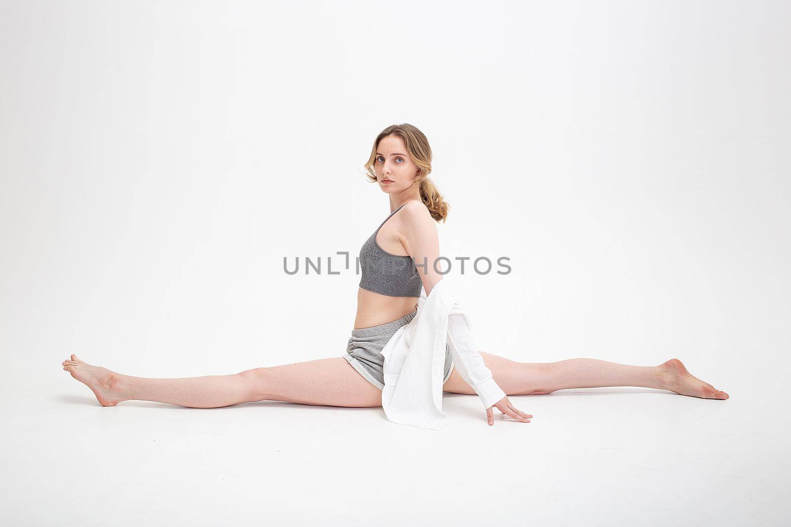 pretty girl practice yoga, doing splits, stretching exercise on white background by artemzatsepilin