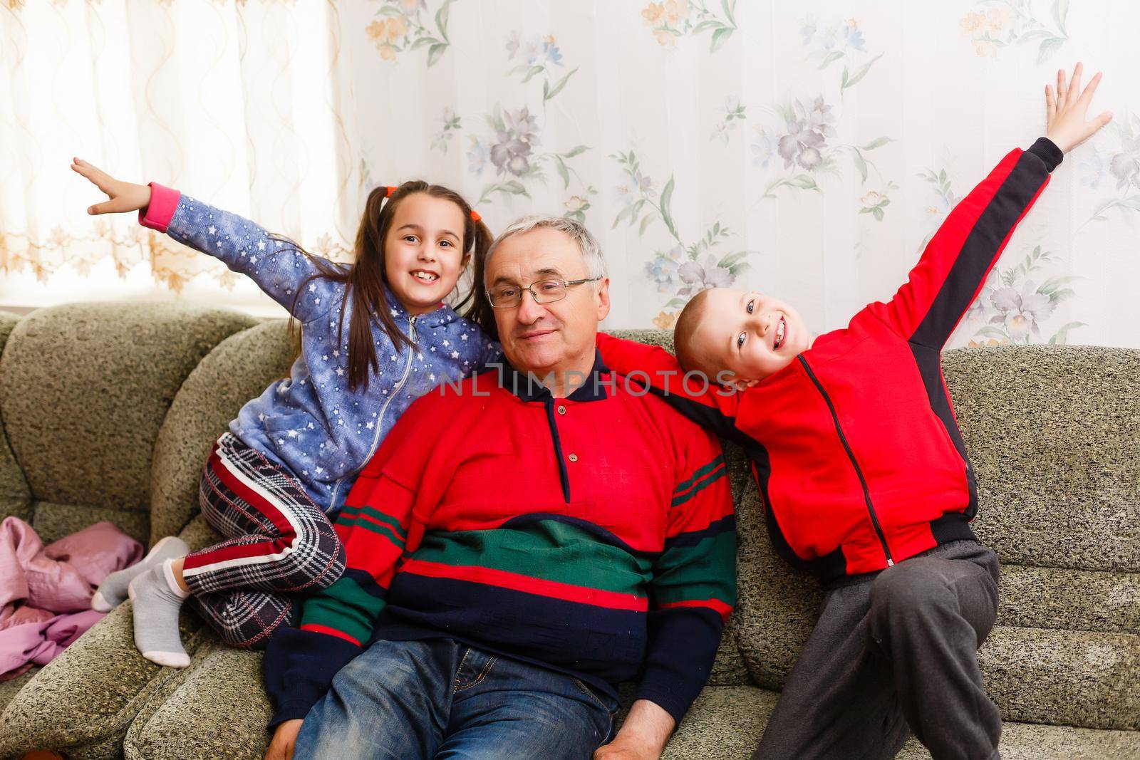 Grandparents spending time with grandchildren on couch by Andelov13