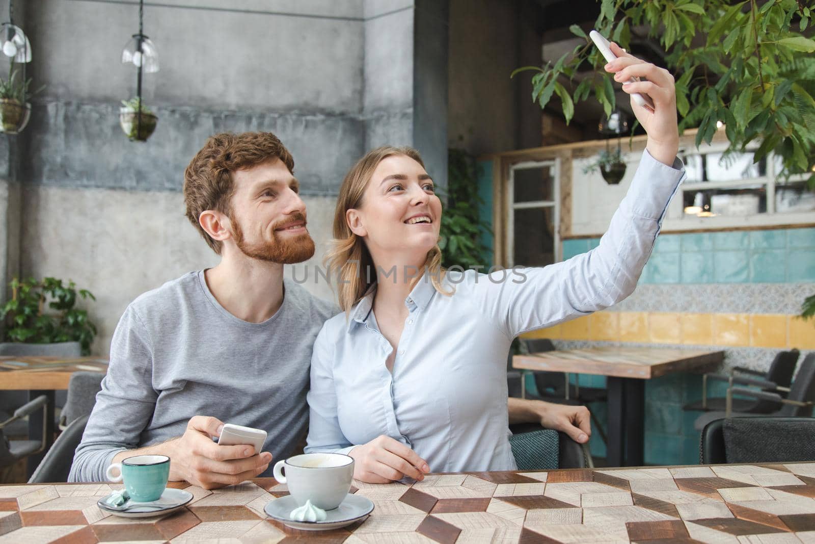 Content man and woman posing for selfie using smarpthone.