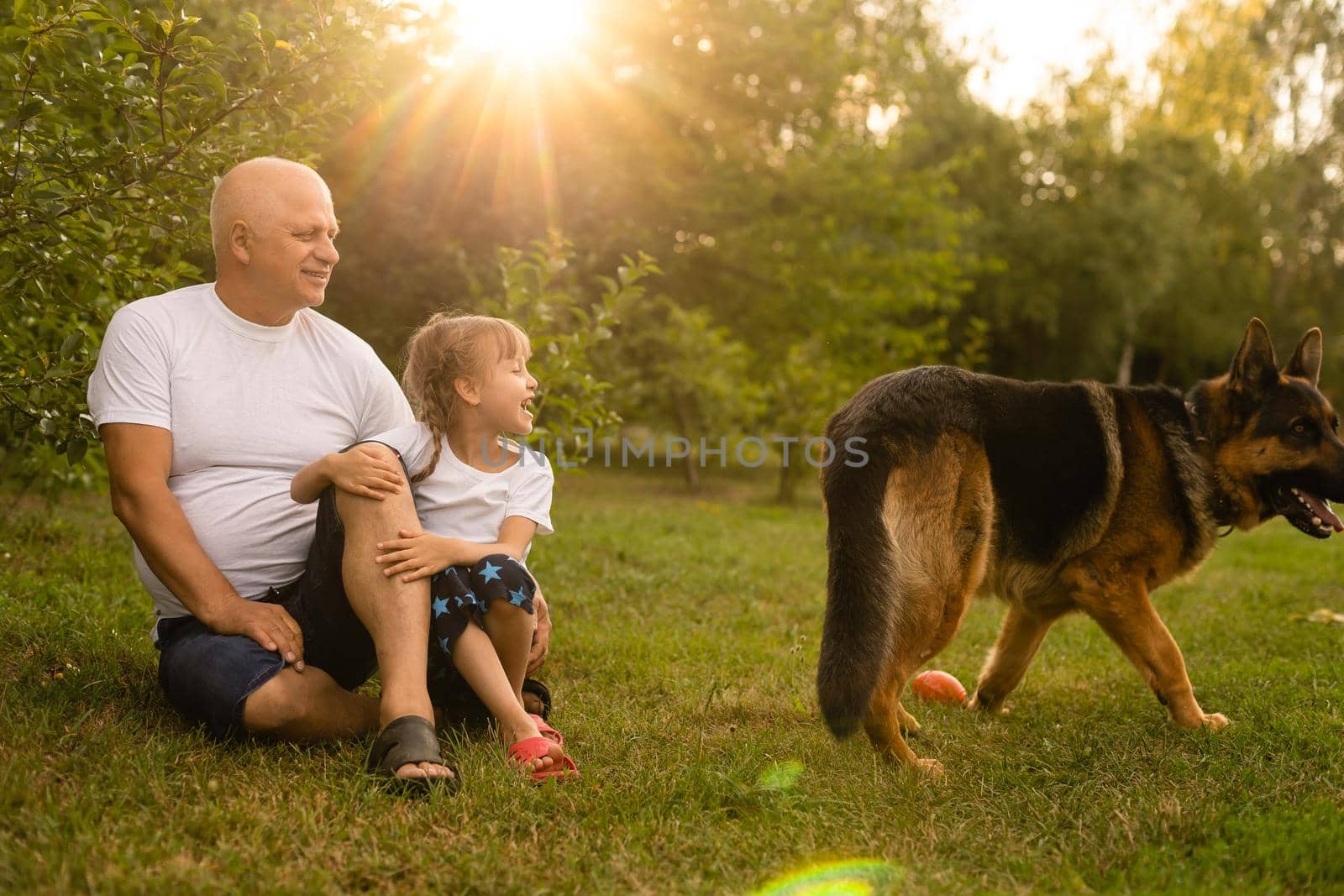 Portrait Of Grandfather With Granddaughter Relaxing Together in the garden