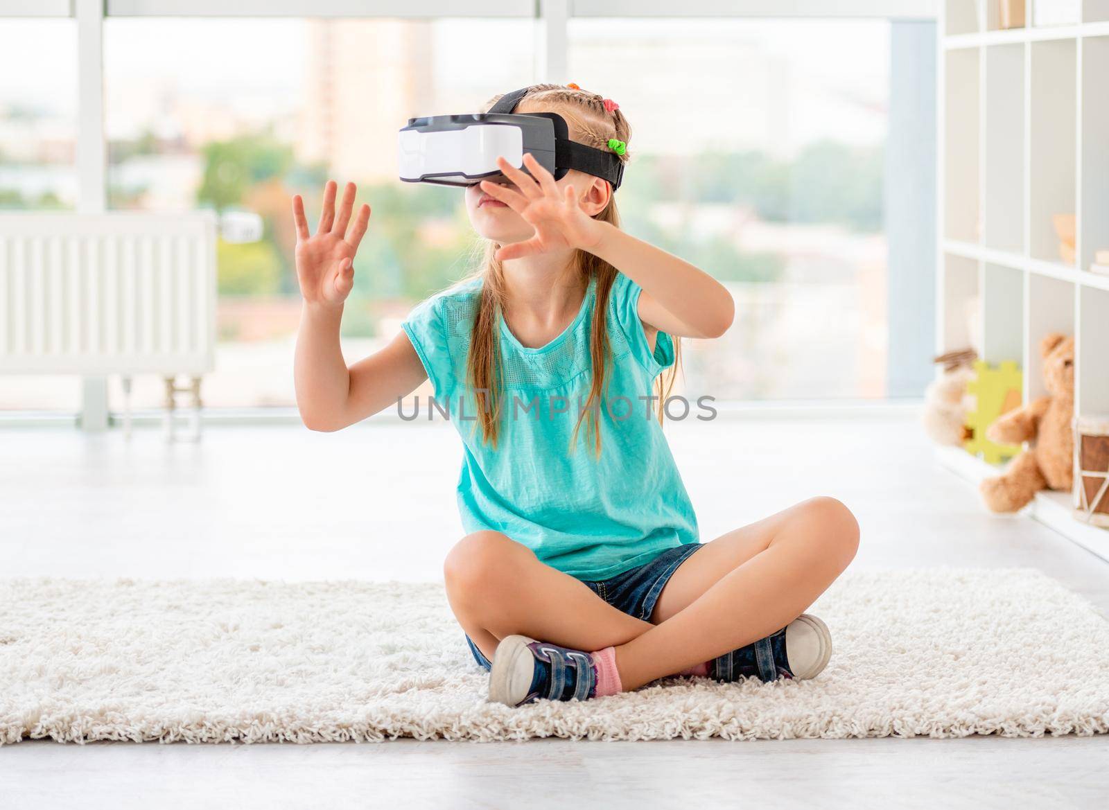 Little girl wearing virtual reality glasses in playing room