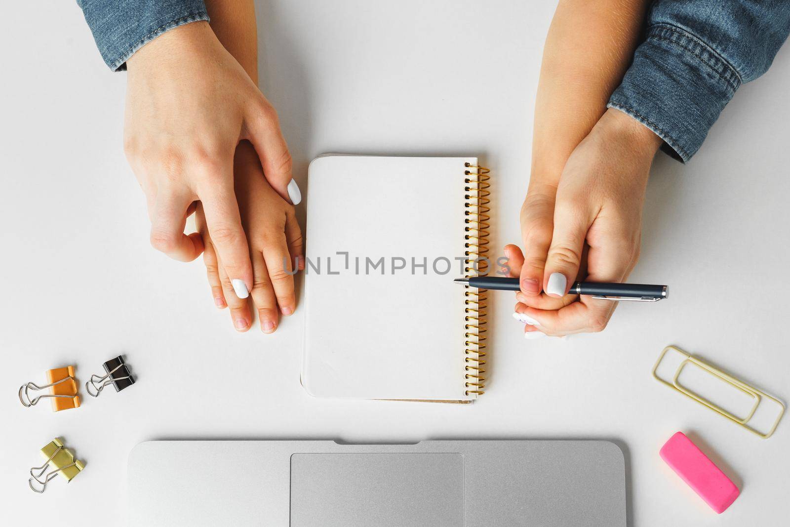 Mother and child hands writing in a notepad, top view, copy space