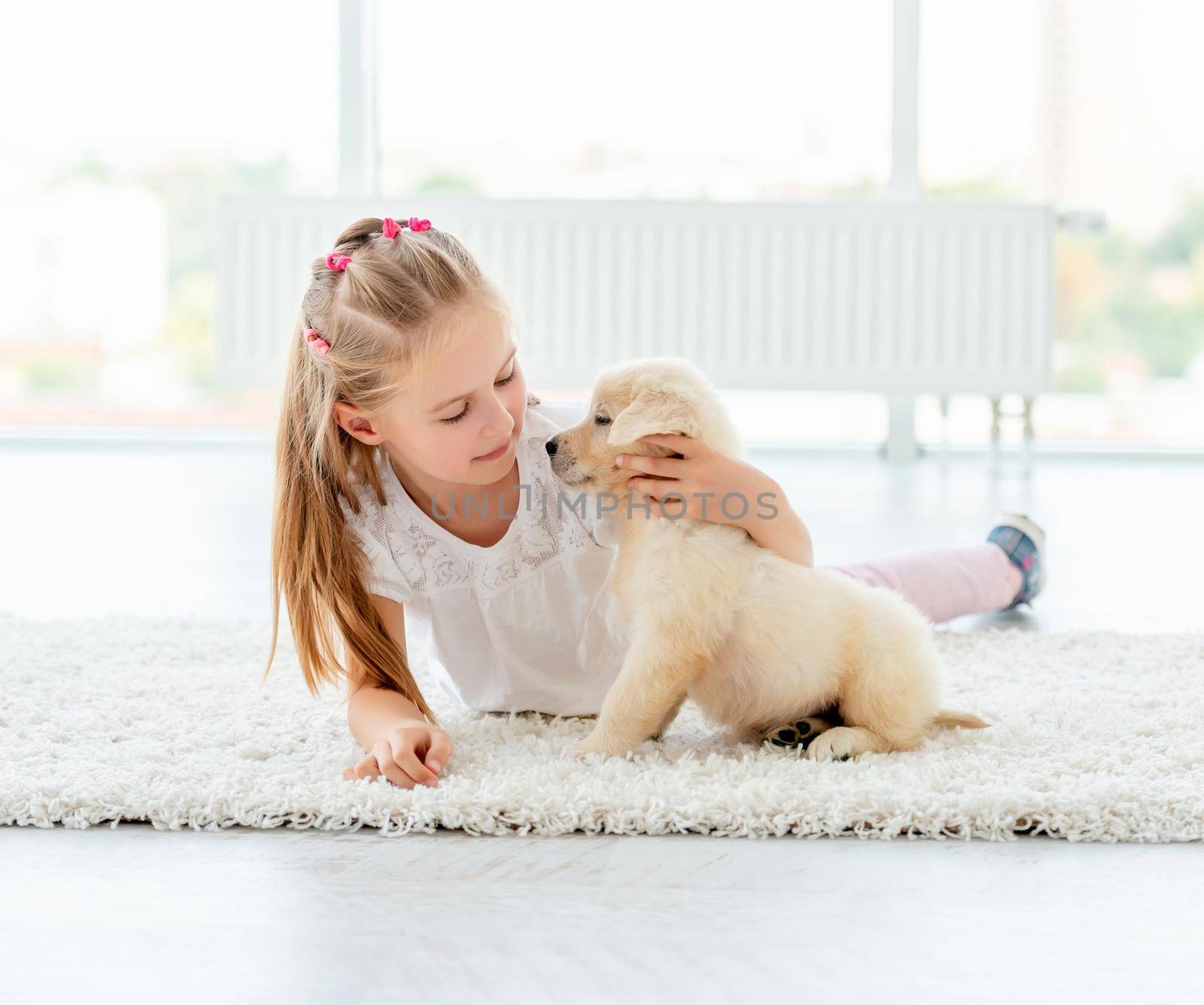 Retriever puppy and cute girl playing at home