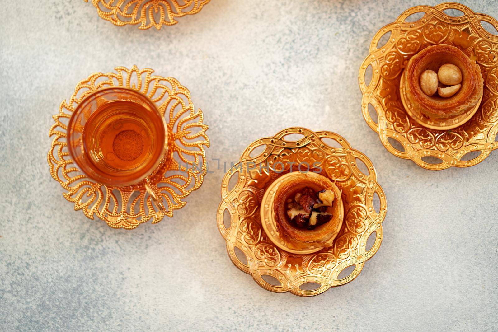 Turkish baklava and Turkish tea in oriental dishes on gray background, close up