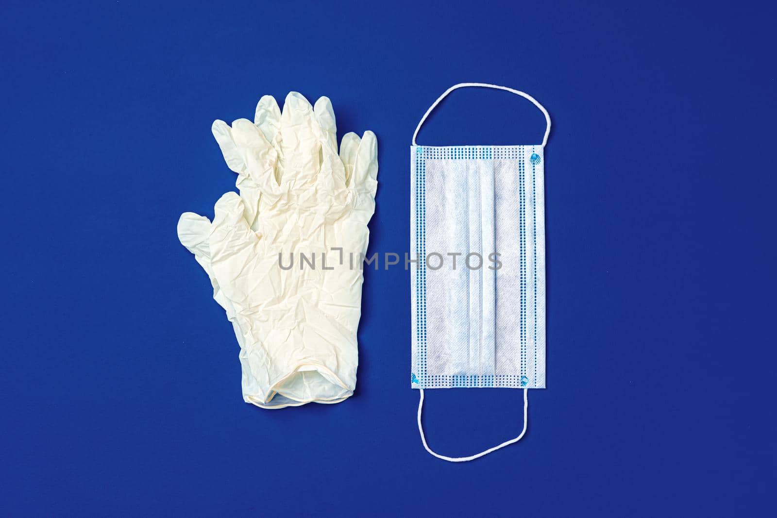 Medical gloves and surgical protective face mask on dark blue background. Coronavirus concept