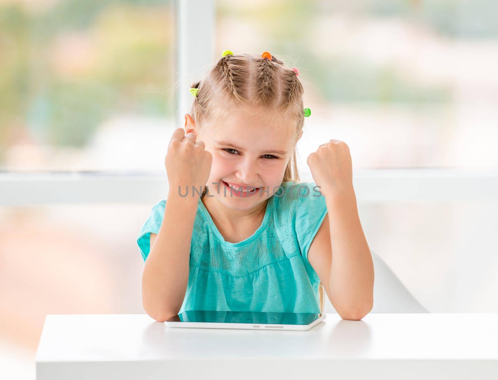 Skilled small girl just won in phone game and making gesture with fists about it