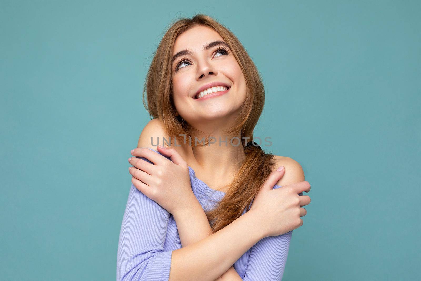 Young smiling happy beautiful dark blonde woman with sincere emotions isolated on background wall with copy space wearing casual blue crop top. Positive concept by TRMK