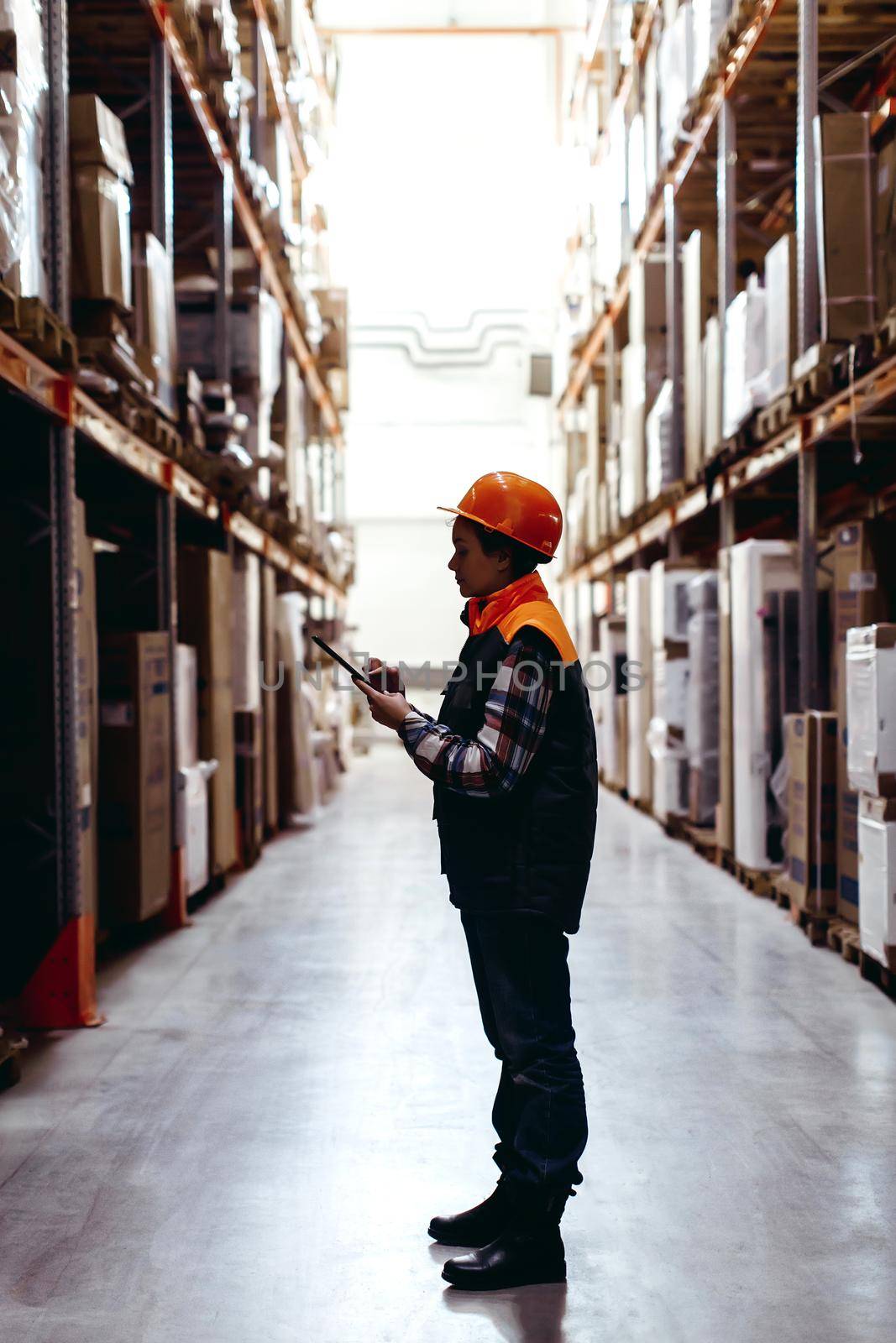 Side view of woman worker standing with papers in warehouse.