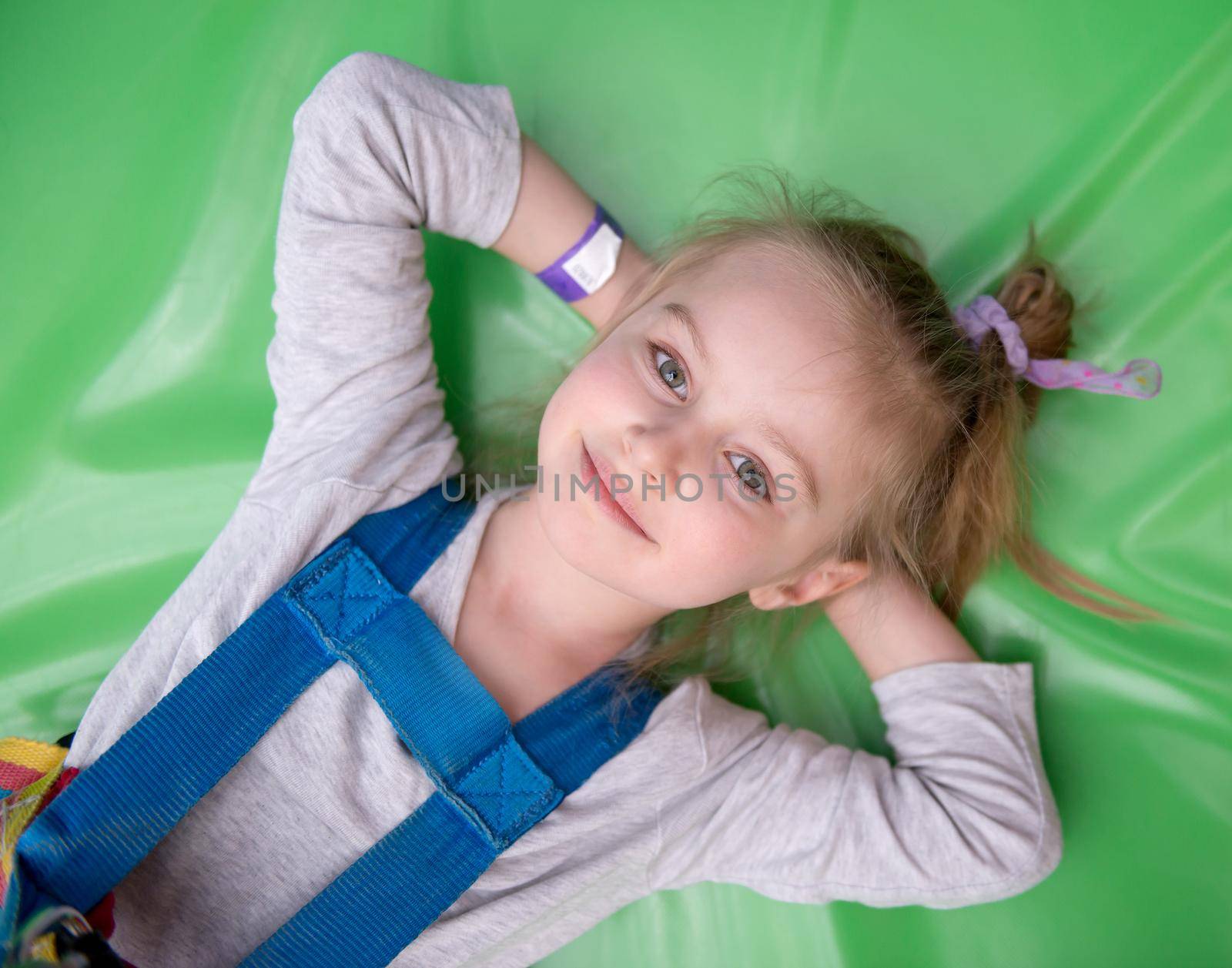 Little smiling girl laying on green soft play gym mat