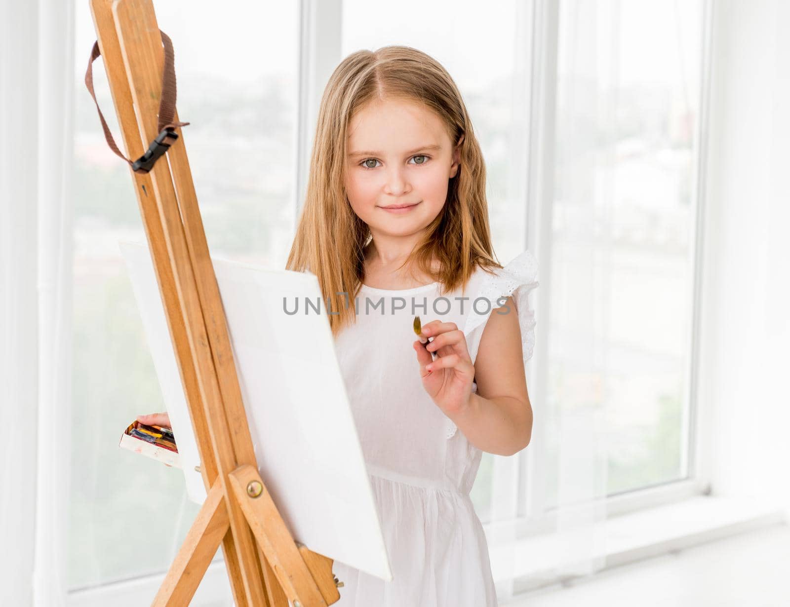 Portrait of a beautiful little girl drawing on easel. Creative child girl making a picture