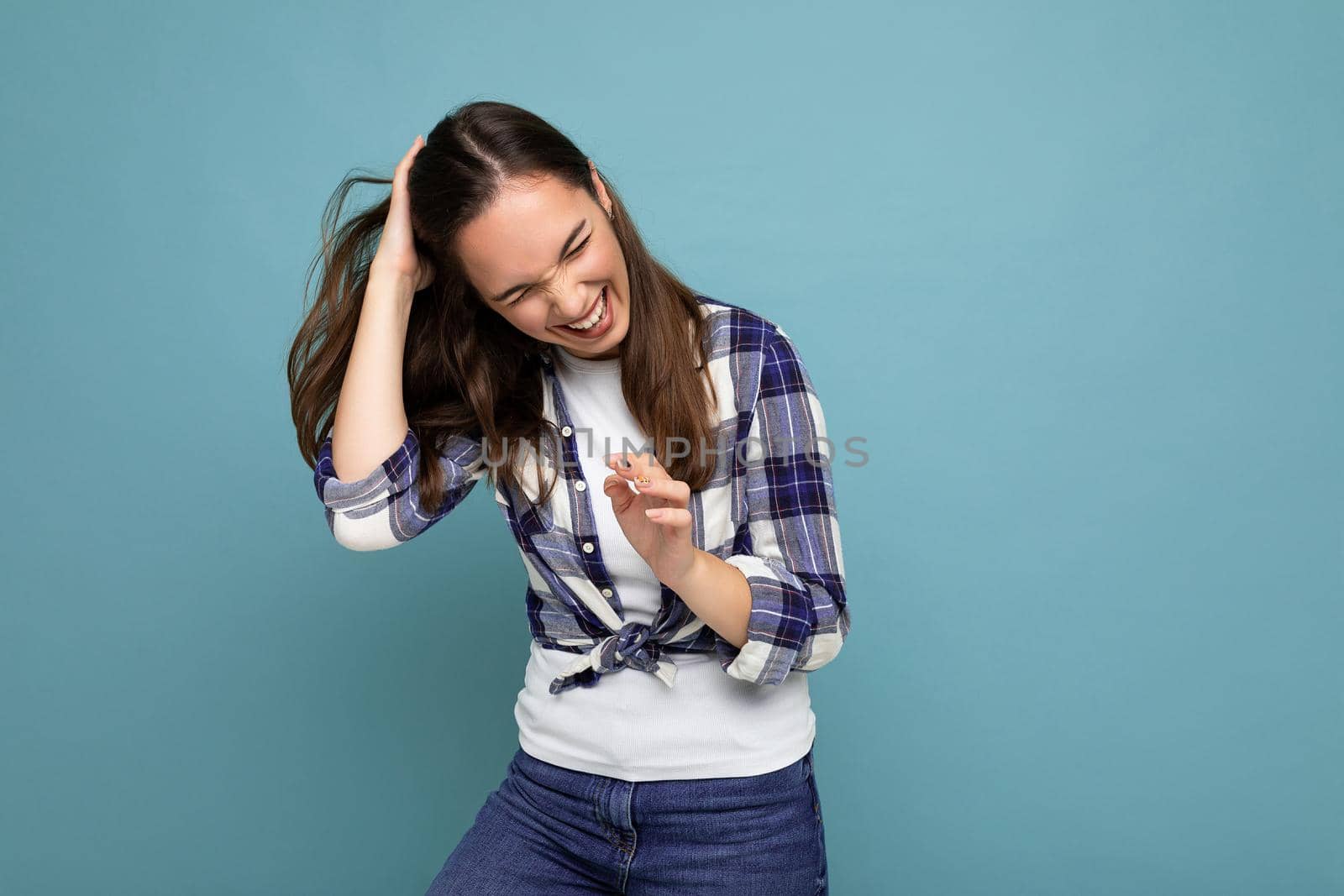 Photo of young positive happy smiling beautiful woman with sincere emotions wearing stylish clothes isolated over background with copy space and laughing.