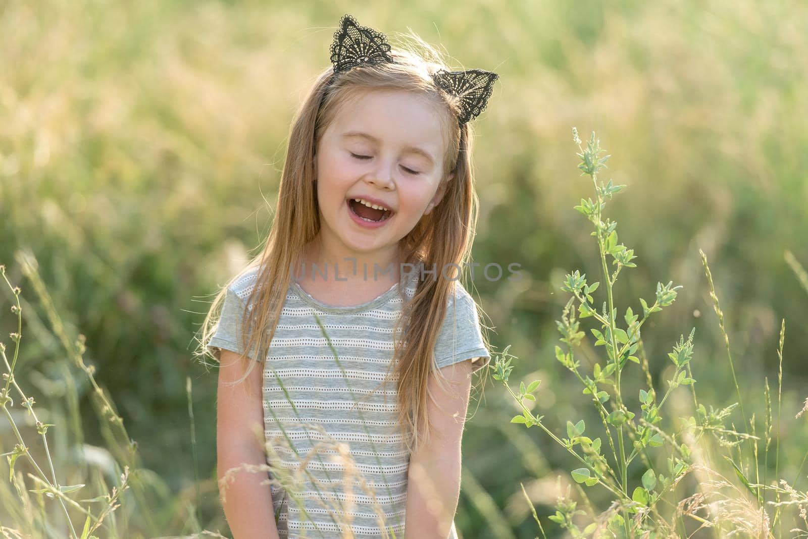 Little happy girl at sunset in the field