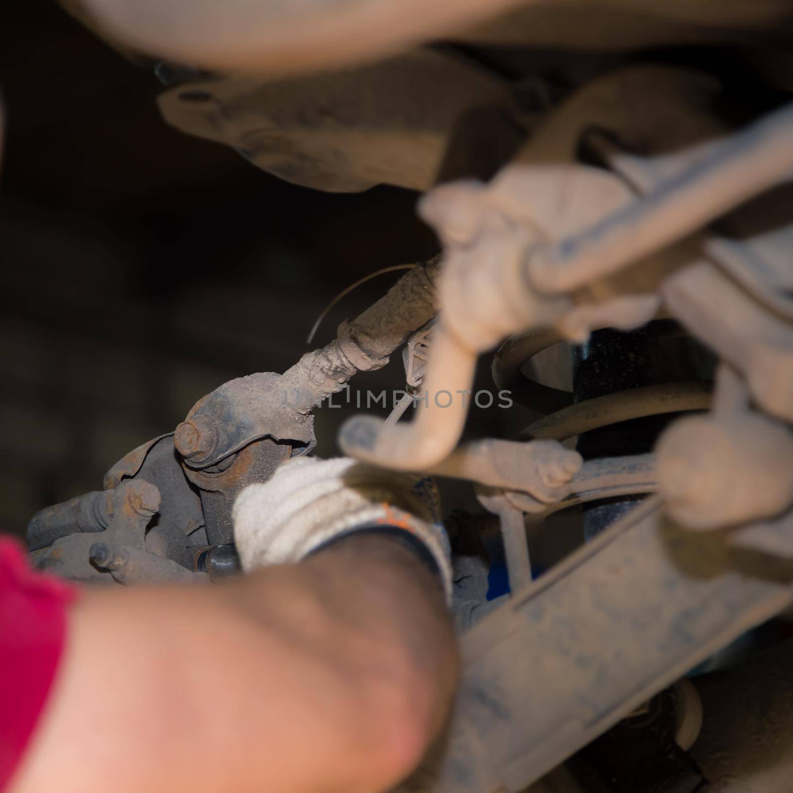 The man's hands unscrew the silent block in the chassis of the car. In the garage, a man changes parts on a vehicle. Small business concept, car repair and maintenance service. UHD 4K.