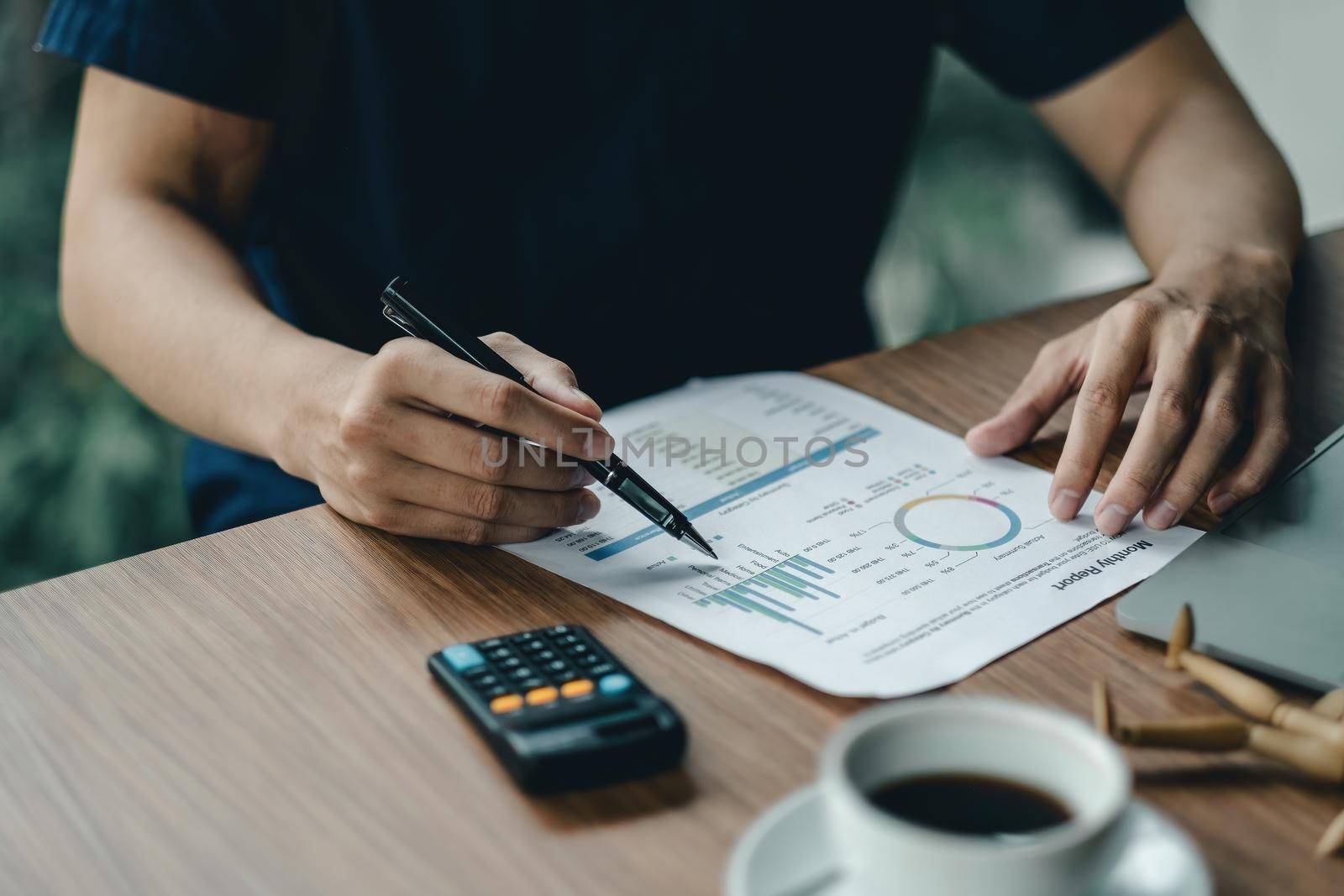 Close up businessman hand holding pen and pointing at financial paperwork, financial calculation concept by nateemee